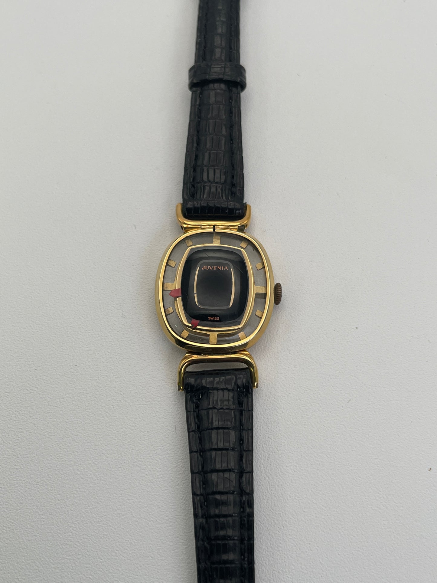 Front view of Juvenia Mystere Skeleton Watch with a black dial, unique red markers, and a gold case on a black leather strap.