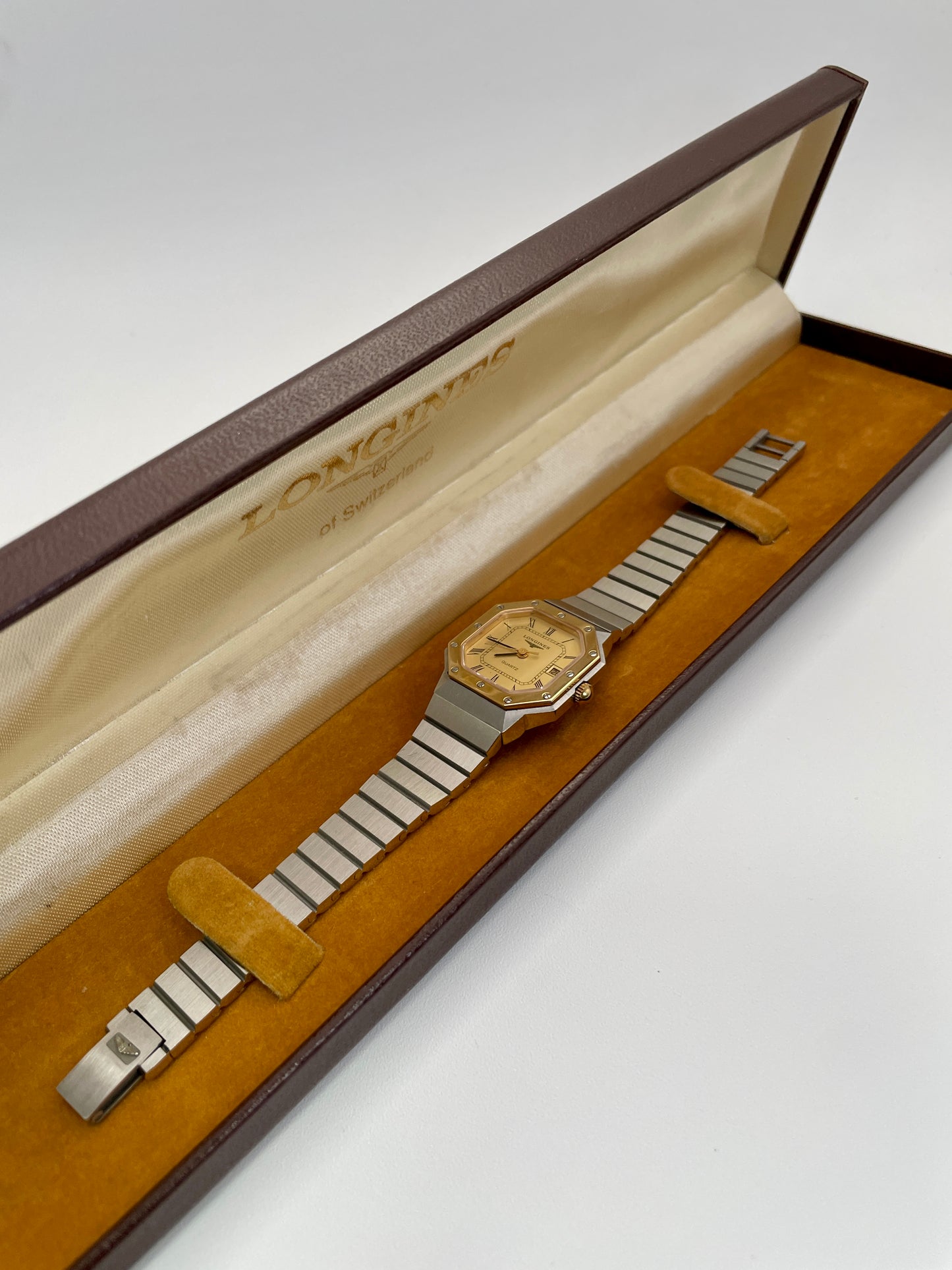 Image of a 1980s Longines Octagon "Royal Oak" ladies quartz watch with a gold-tone dial, bezel screws, and a stainless steel bracelet, presented in its original Longines box.