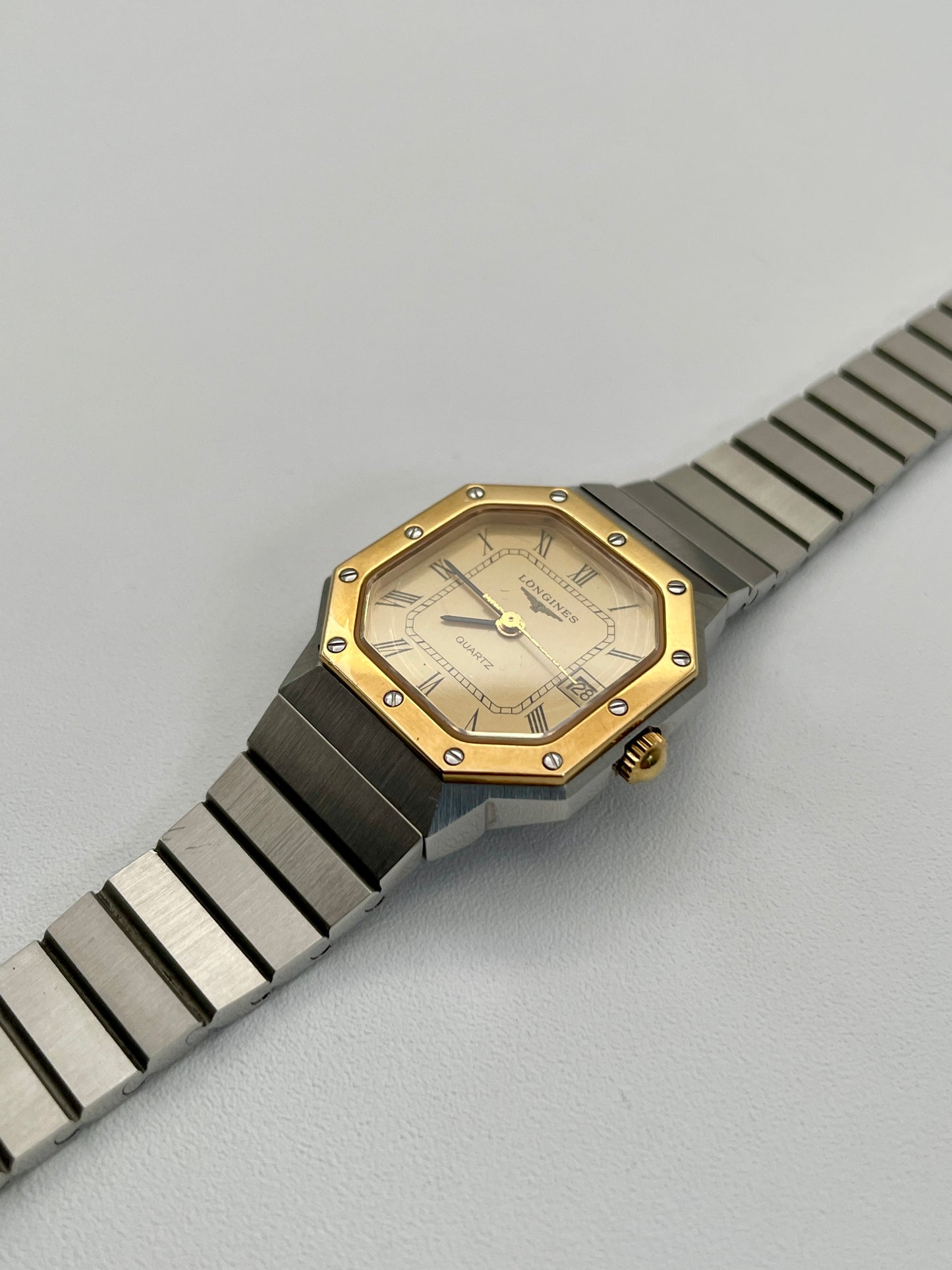 Diagonal view of the 1980s Longines Octagon "Royal Oak" ladies quartz watch, highlighting the gold-tone dial, bezel screws, and integrated stainless steel bracelet.