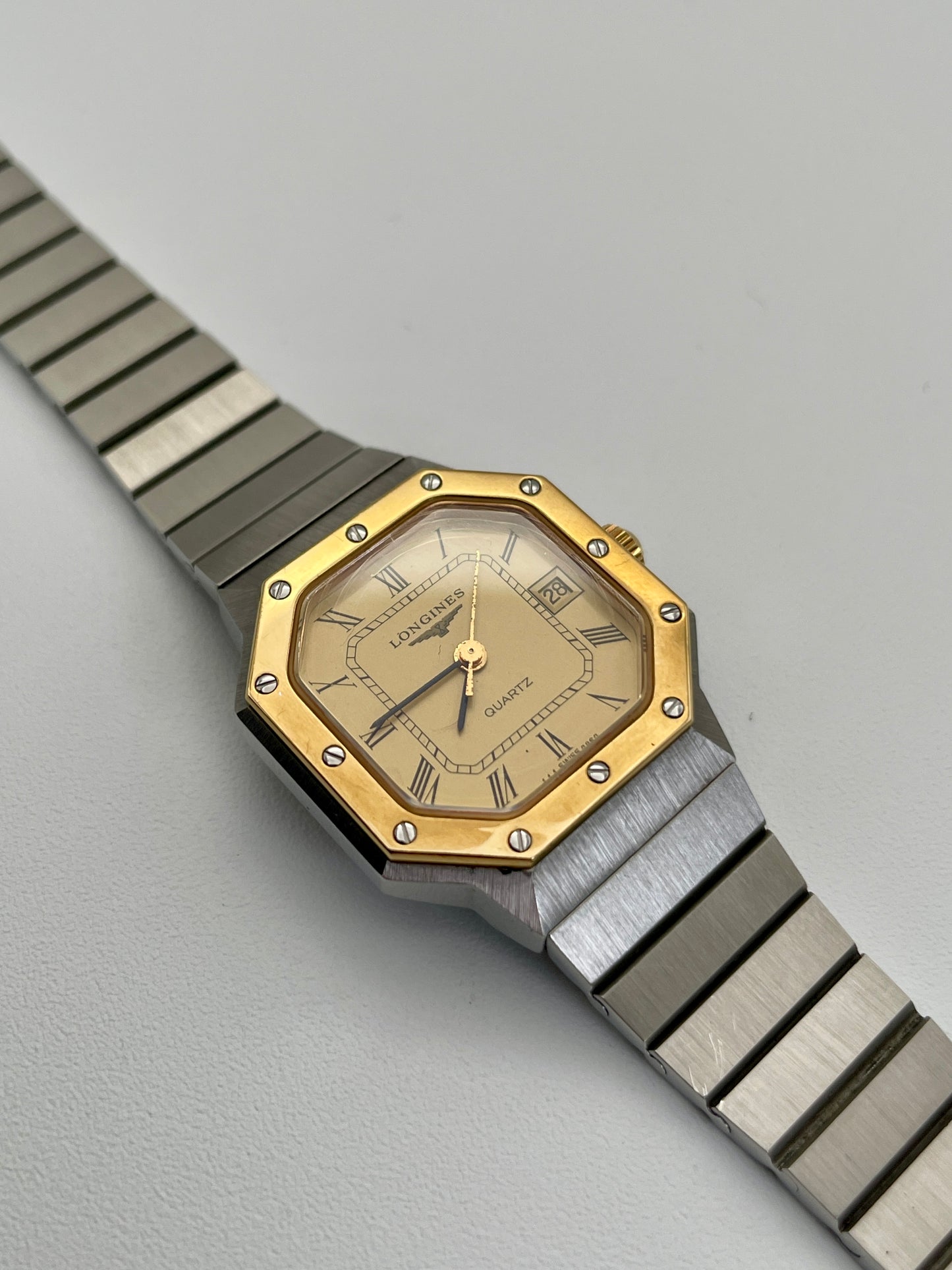 1980s Longines Octagon "Royal Oak" ladies quartz watch with a gold-tone dial, bezel screws, and a stainless steel bracelet.
