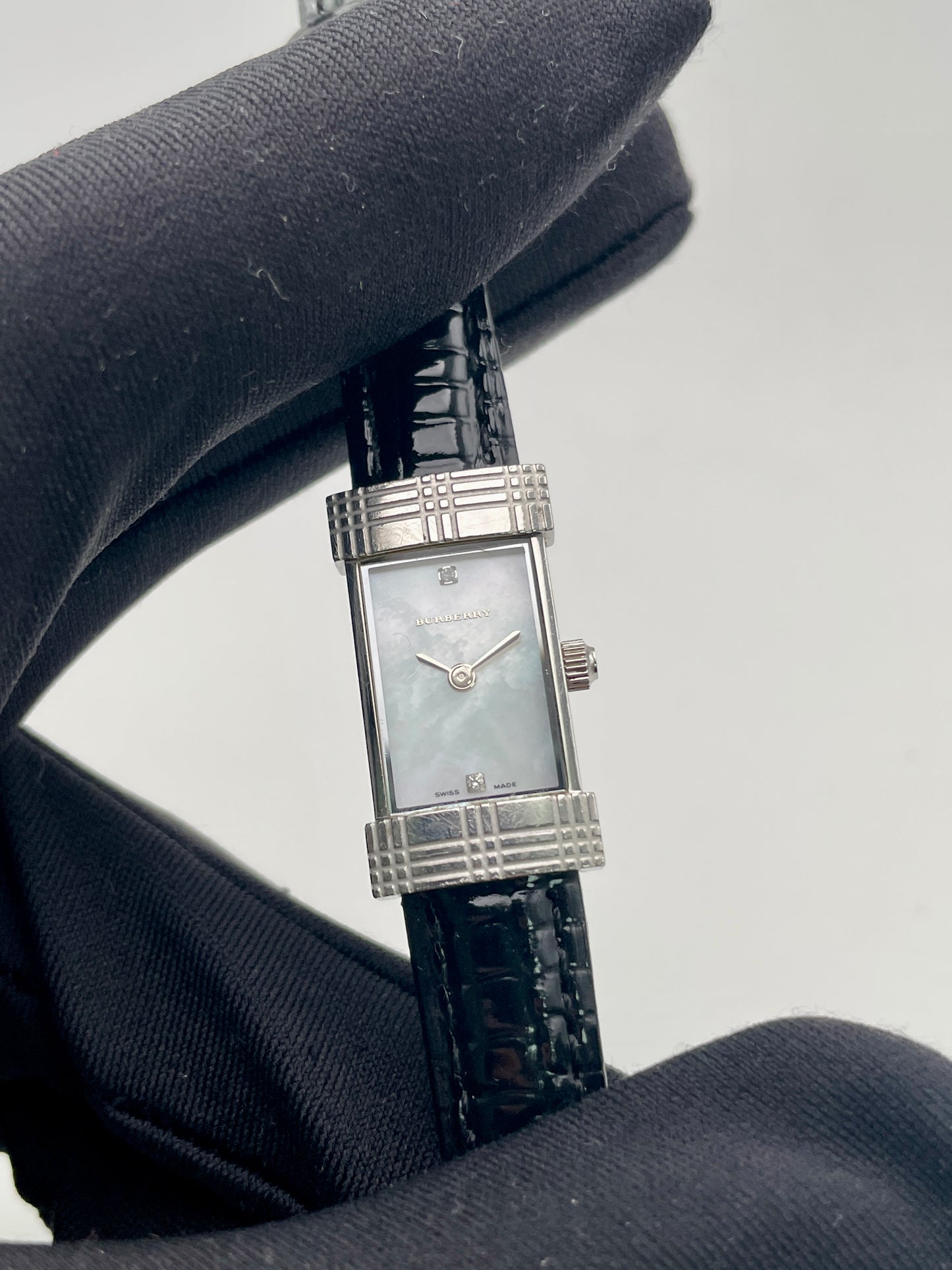 Close-up view of Burberry vintage watch held in gloved hand, showing dial and bezel details
