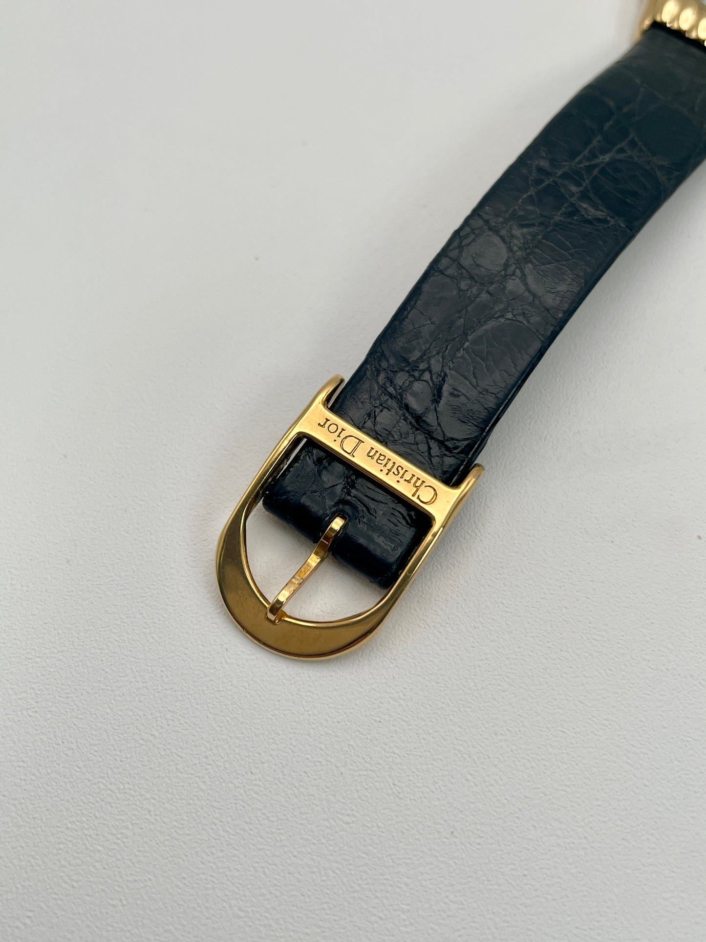 Close-up of Christian Dior 3049 watch's branded gold-tone buckle and embossed black leather strap.