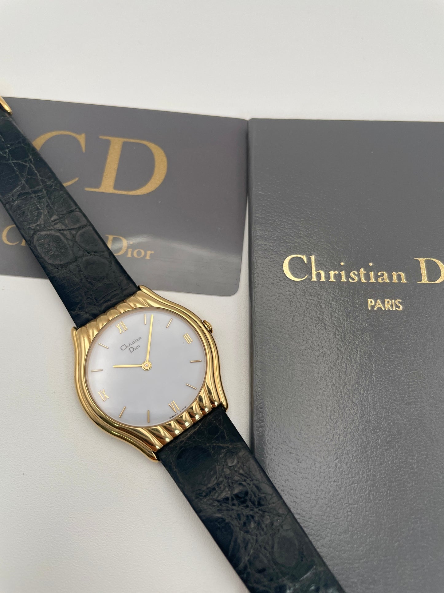 Christian Dior 3049 gold-tone watch paired with black leather strap, shown with original packaging and paperwork.