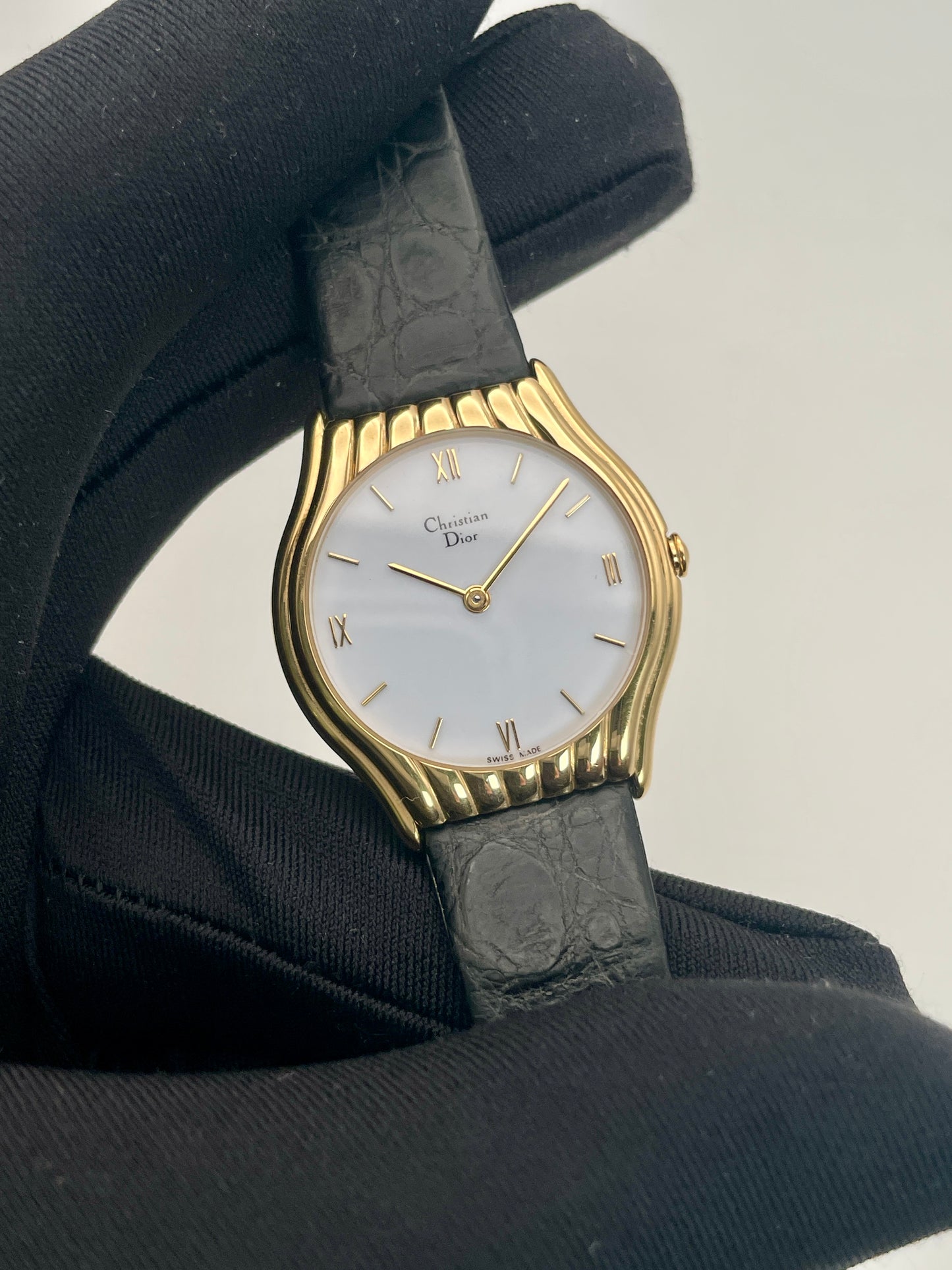 Christian Dior 3049 watch with gold case and mother-of-pearl dial held in a gloved hand for display.