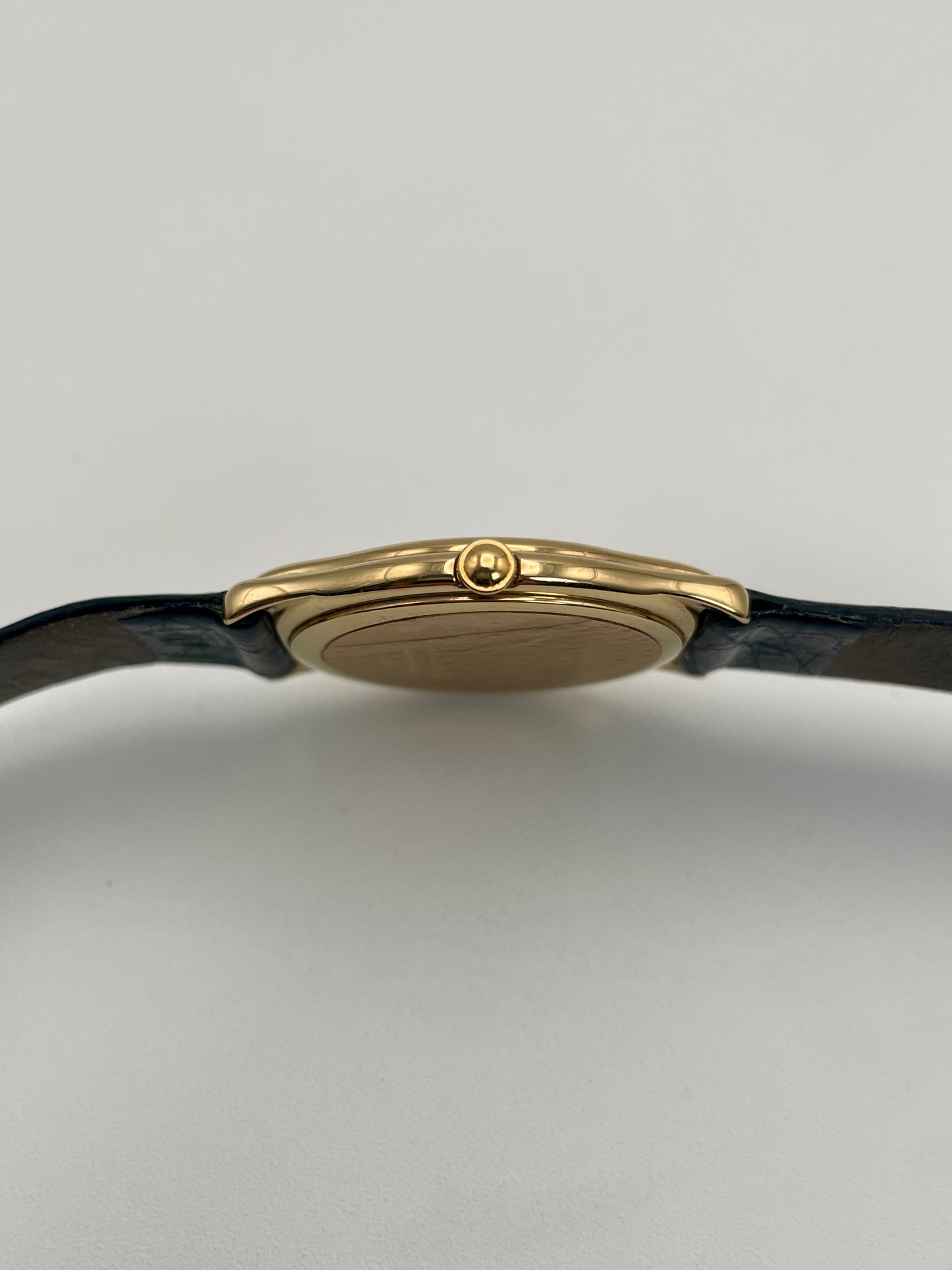 Crown side view of Christian Dior 3049 gold-tone watch highlighting its crown, sleek case design and black leather strap.