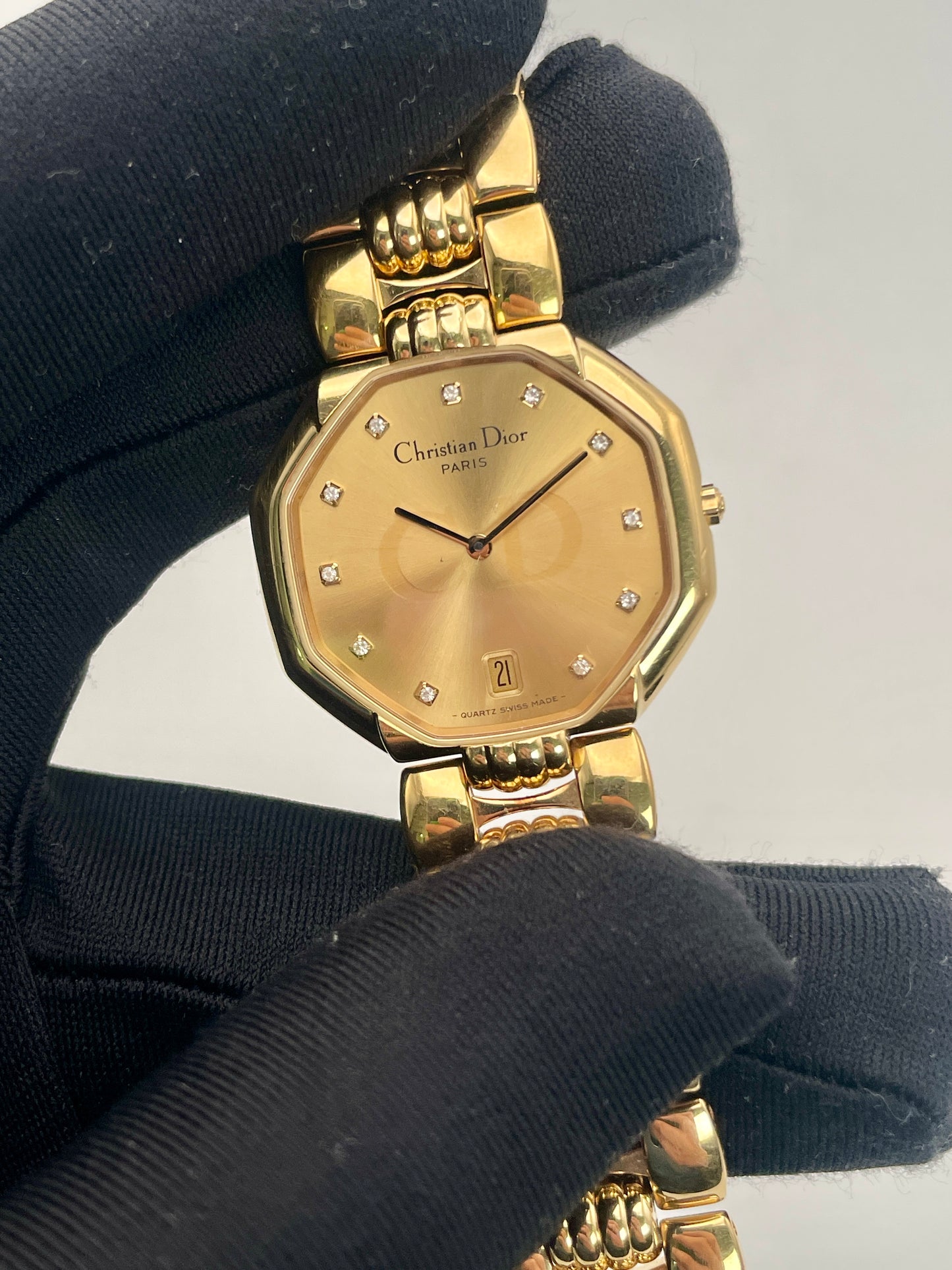 Close up view of Christian Dior Depose Vintage Women's Watch in gold, held in hand, showing the elegant dial with diamond markers and date display.
