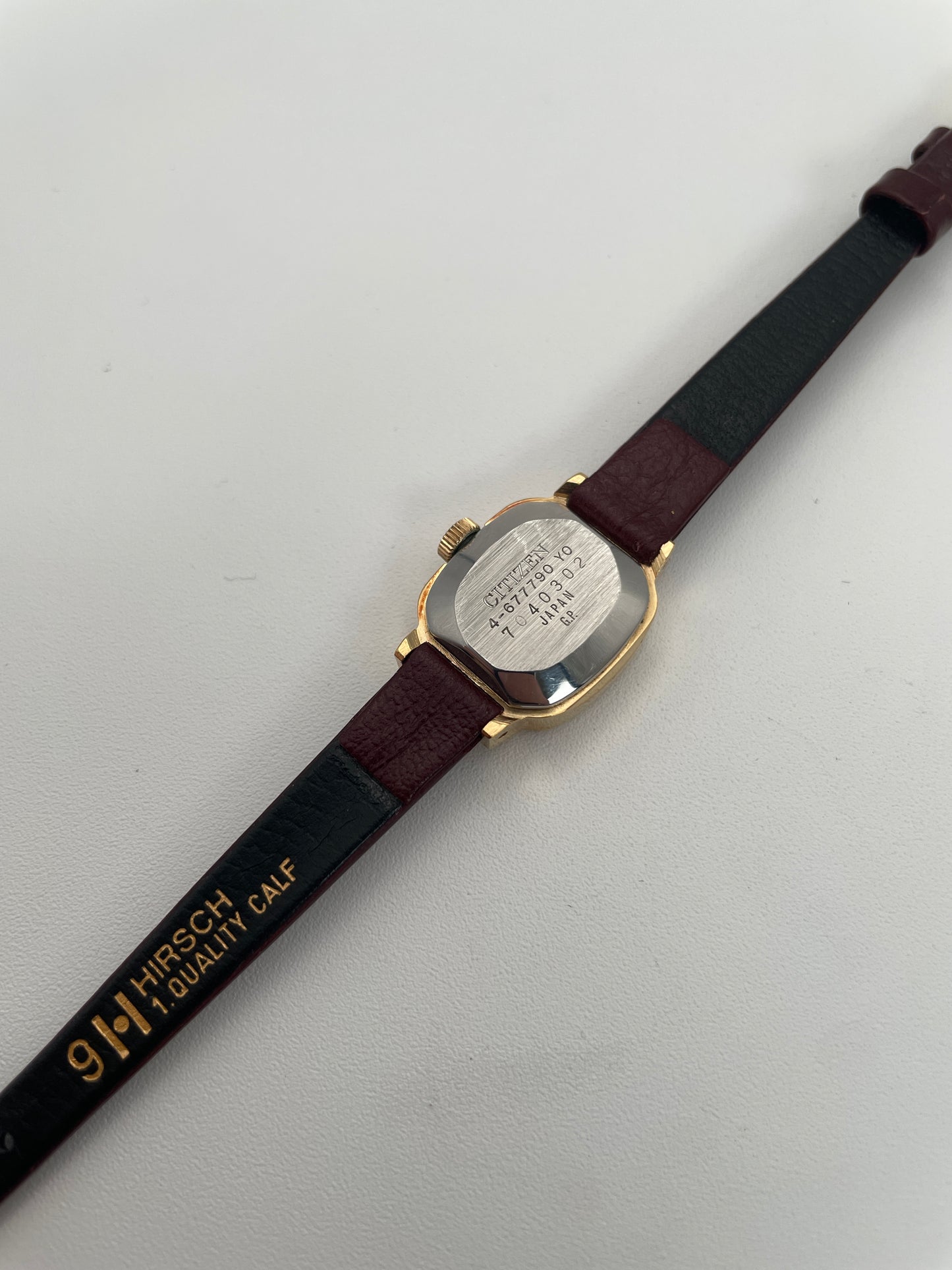 Caseback view of a vintage Citizen ladies watch with a textured gold bezel and burgundy leather strap.