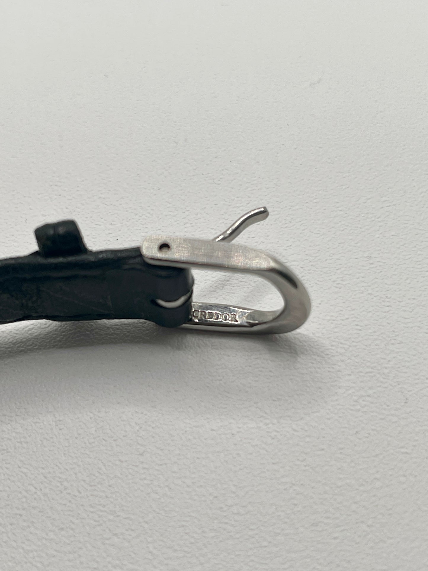 Close-up view of the Credor watch buckle with black leather strap