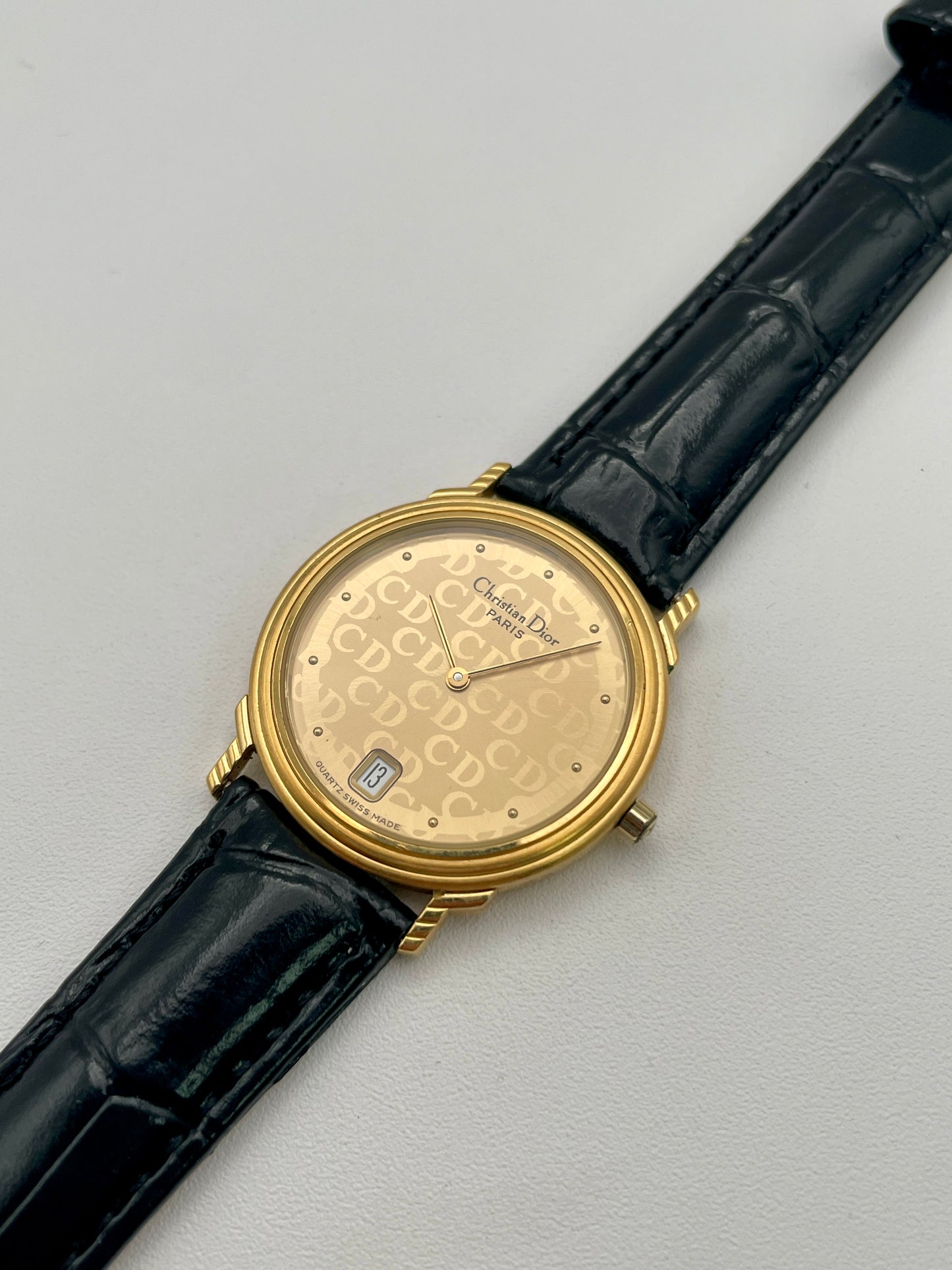 Christian Dior 45.122 vintage women's watch in gold case with gold CD dial and black strap, diagonal angle