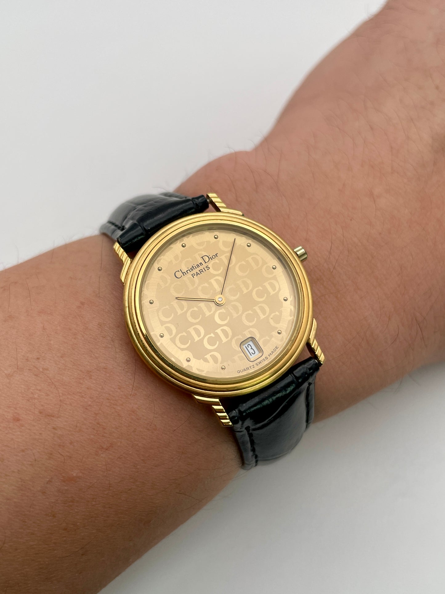 Christian Dior 45.122 gold watch on wrist, showcasing slim gold-tone case and CD dial pattern