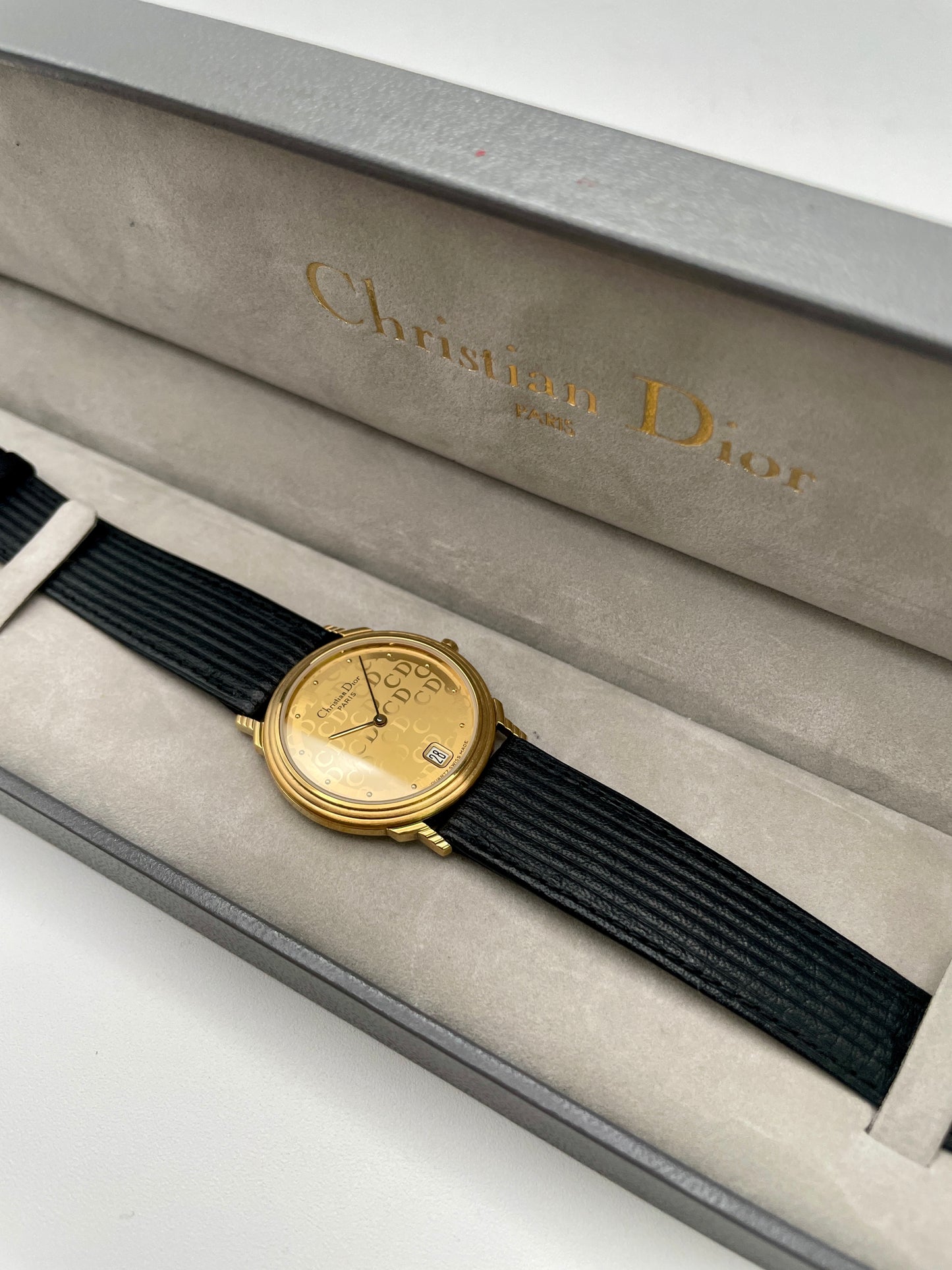 Christian Dior 45.122 vintage women's watch in gold with monogram dial and black ribbed strap, shown inside original Dior box