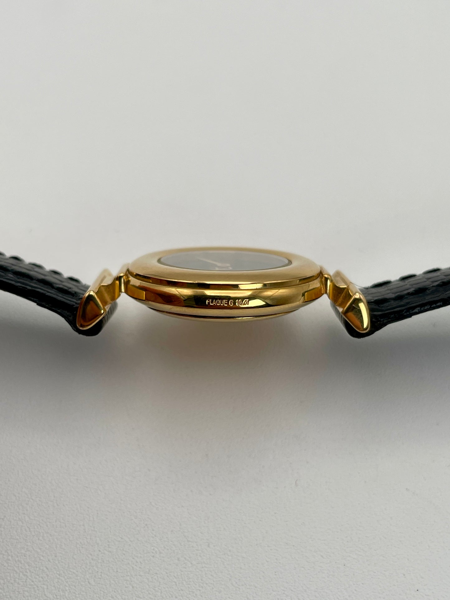 Side view of the Fendi 320L watch with a gold-tone round case and black leather strap