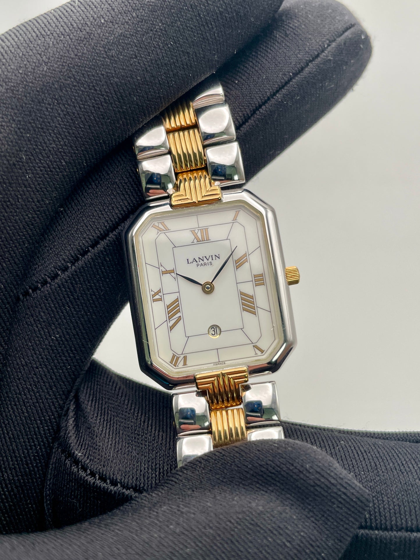 Close-up handheld view of Lanvin Paris 516897.B focusing on white dial with gold-tone hands