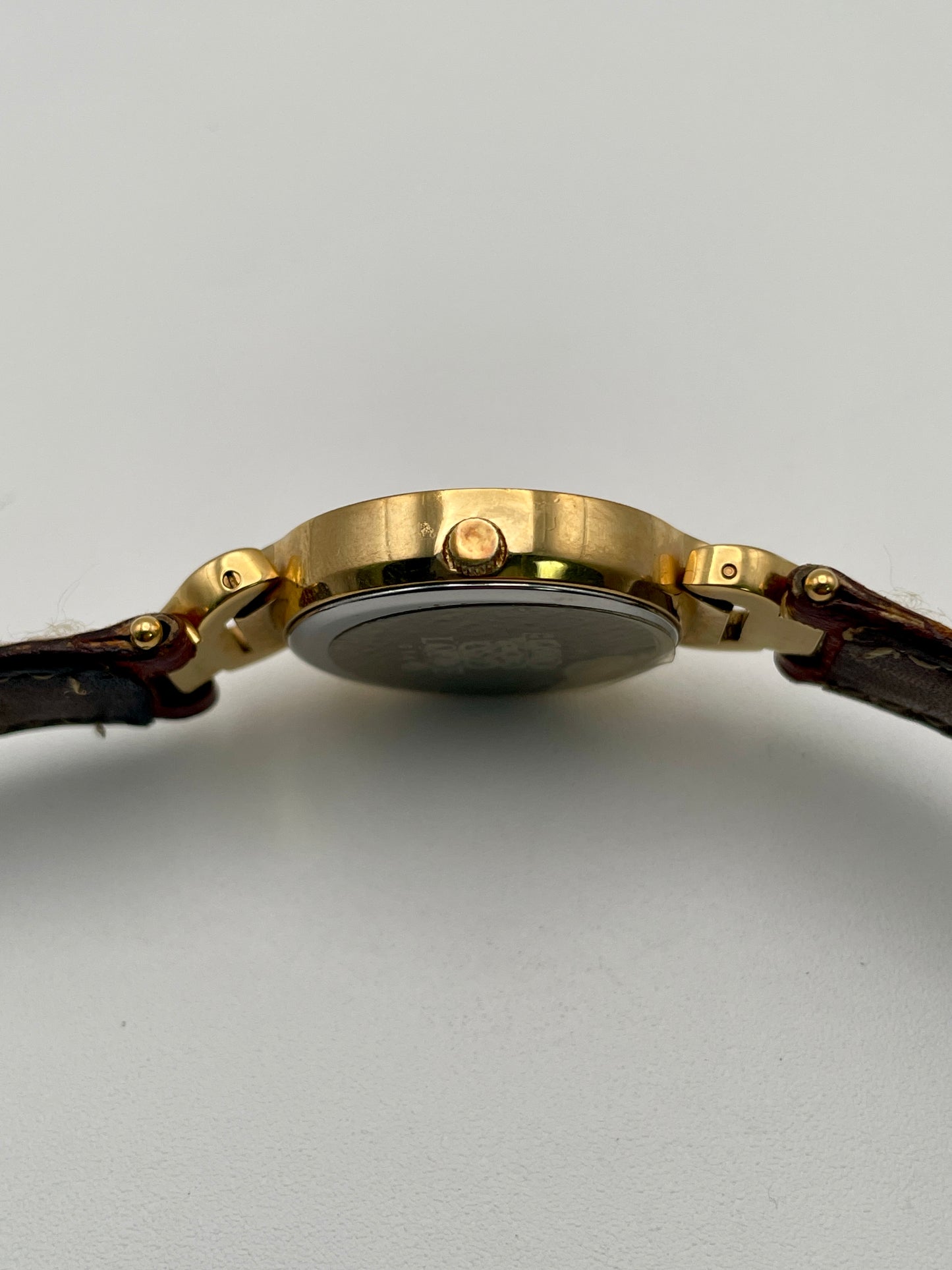 Side view focusing on the gold crown of the Loewe vintage women's watch with a smooth bezel.