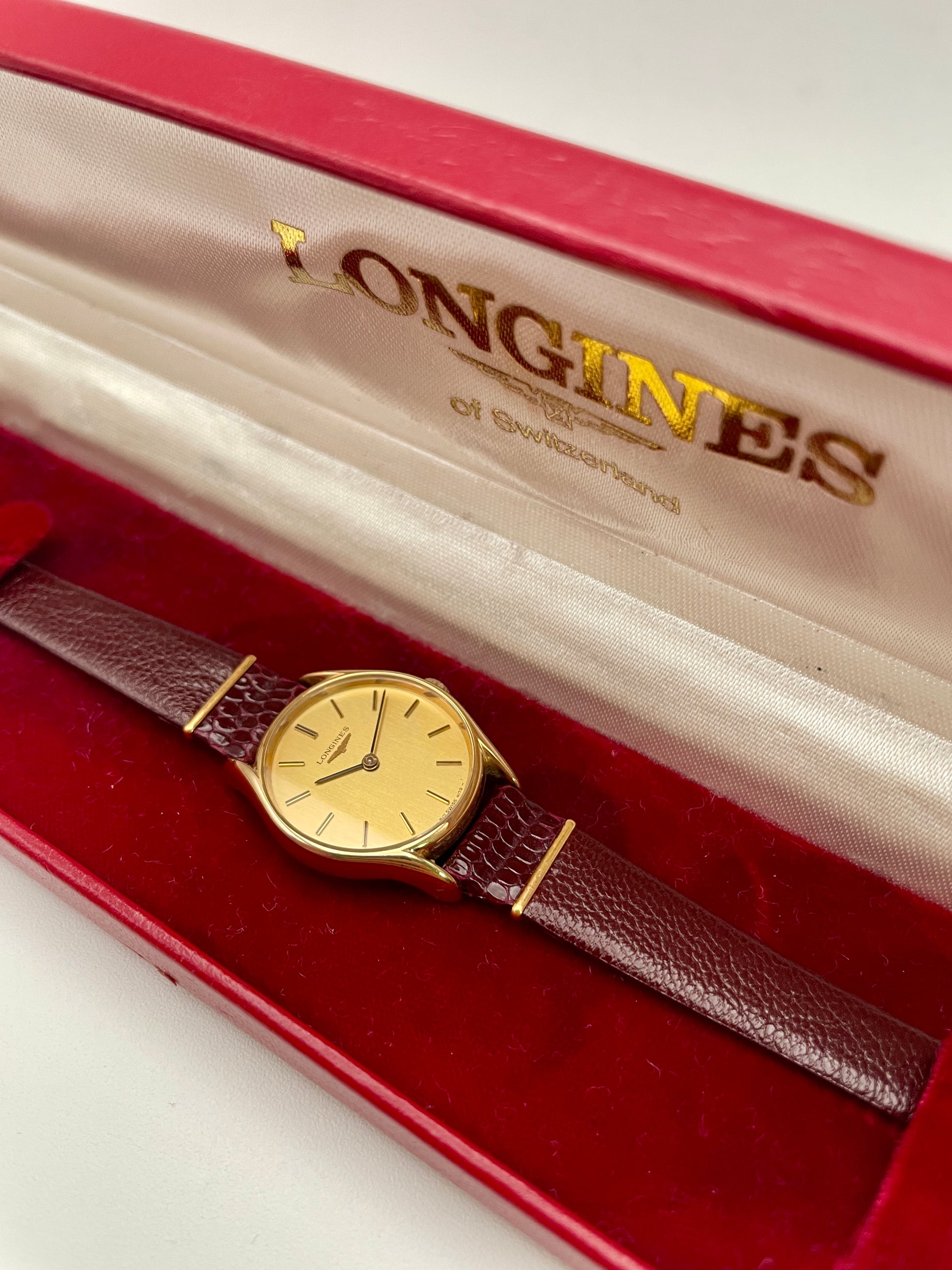 Longines Ref. 4139 vintage women's watch in gold with a burgundy strap, elegantly presented in its red Longines box.