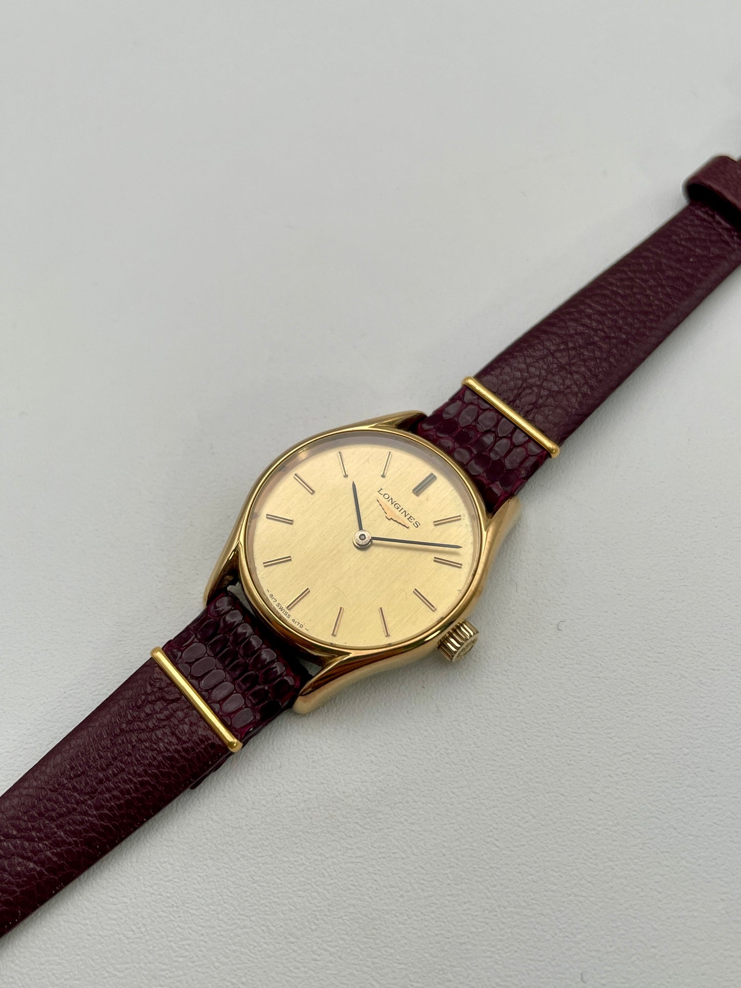 Longines Ref. 4139 vintage women's watch in gold with a burgundy leather strap, showcasing the round case and elegant dial design.