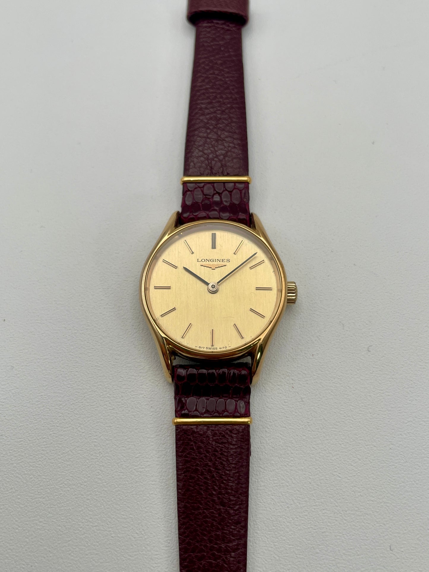 Longines Ref. 4139 vintage women's watch in gold with a burgundy leather strap, showcasing the round case and elegant dial design.