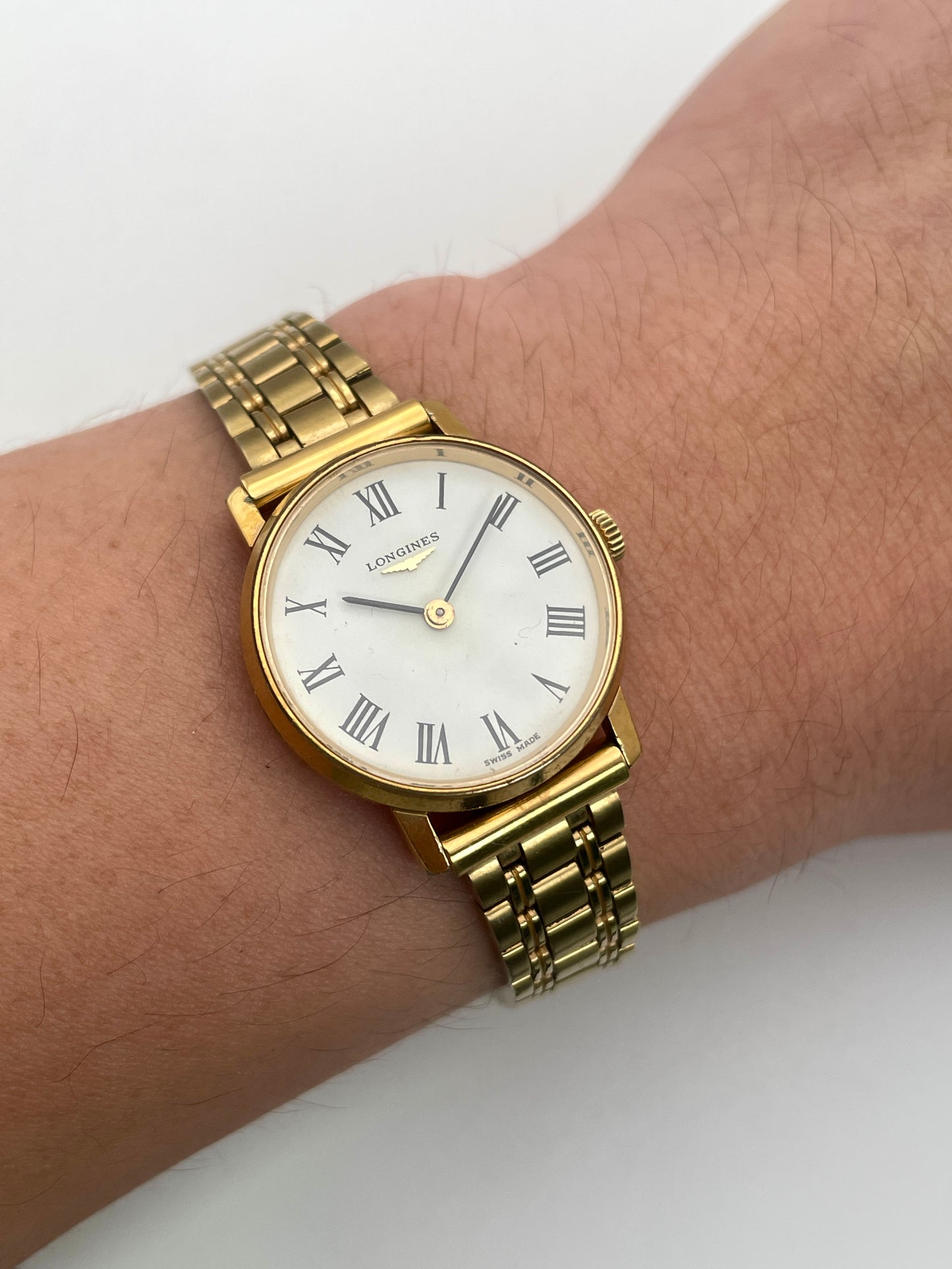 Wrist shot of Longines Classic Vintage Ladies Watch in Gold with white dial and Roman numerals, shown on a wrist.