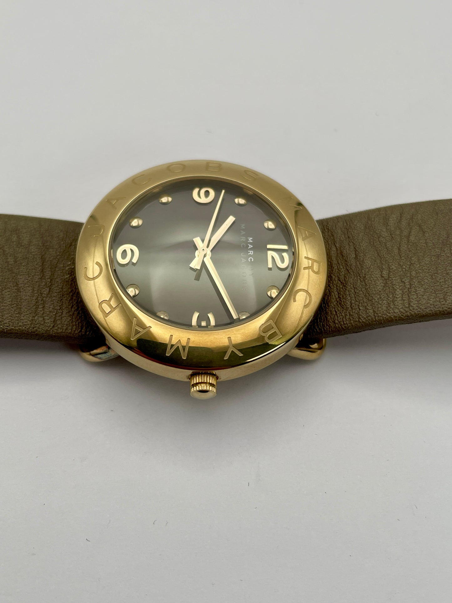 Close-up view of the Marc by Marc Jacobs watch focusing on the gold-tone crown and case with tan leather strap