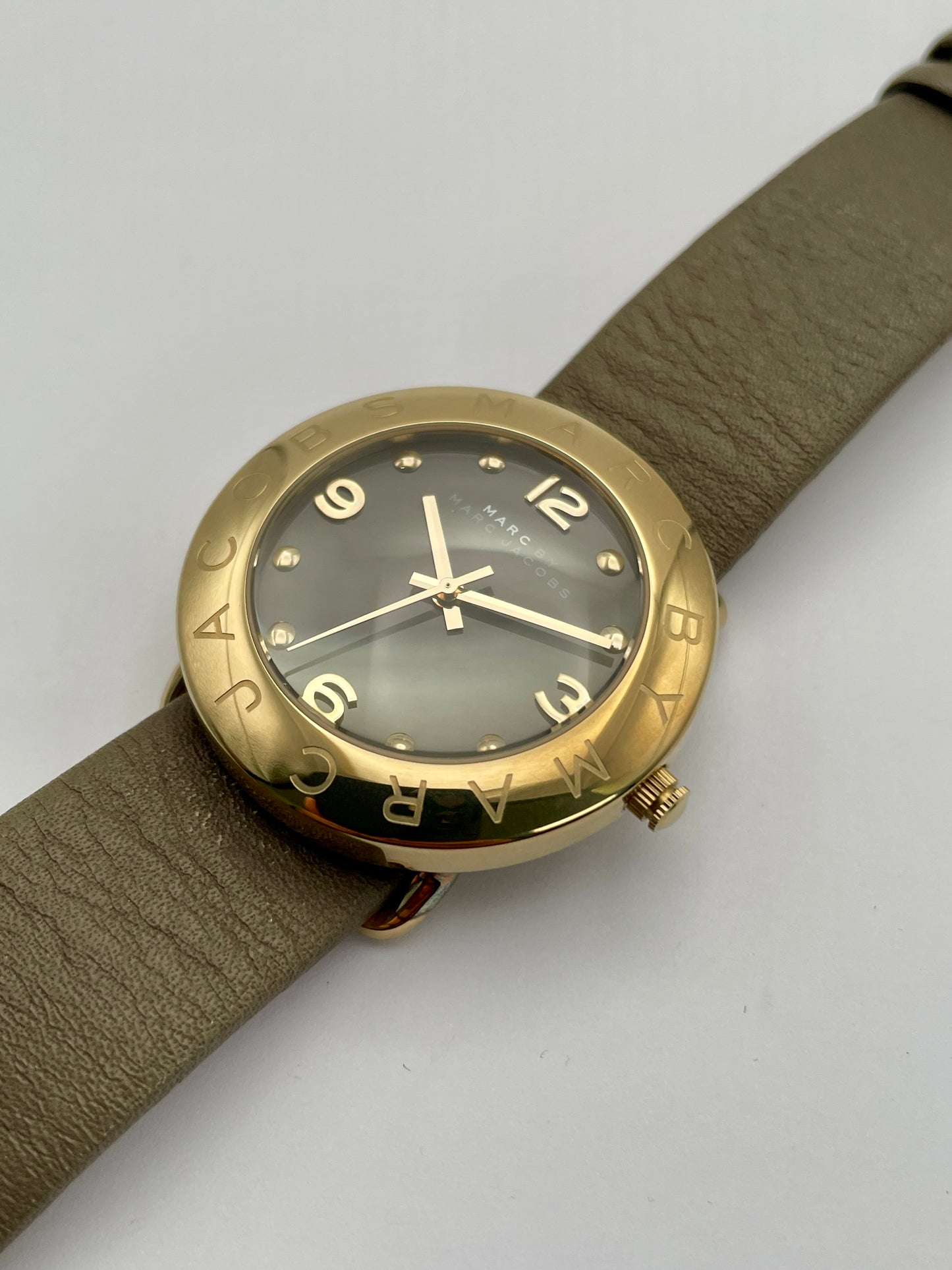 Diagonal view of the Marc by Marc Jacobs watch highlighting the gold-tone case, black dial, and tan leather strap