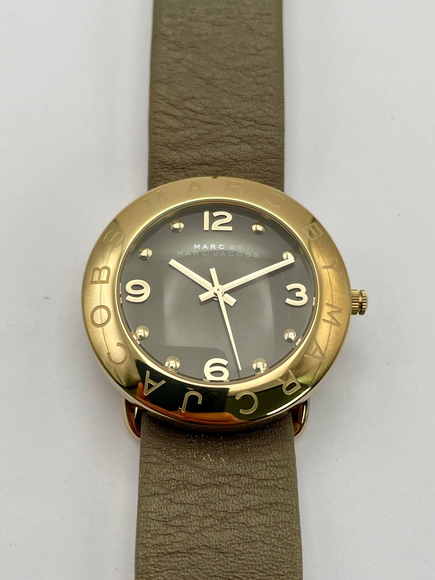 Front view of the Marc by Marc Jacobs watch showing the gold-tone case, black dial, and tan leather strap