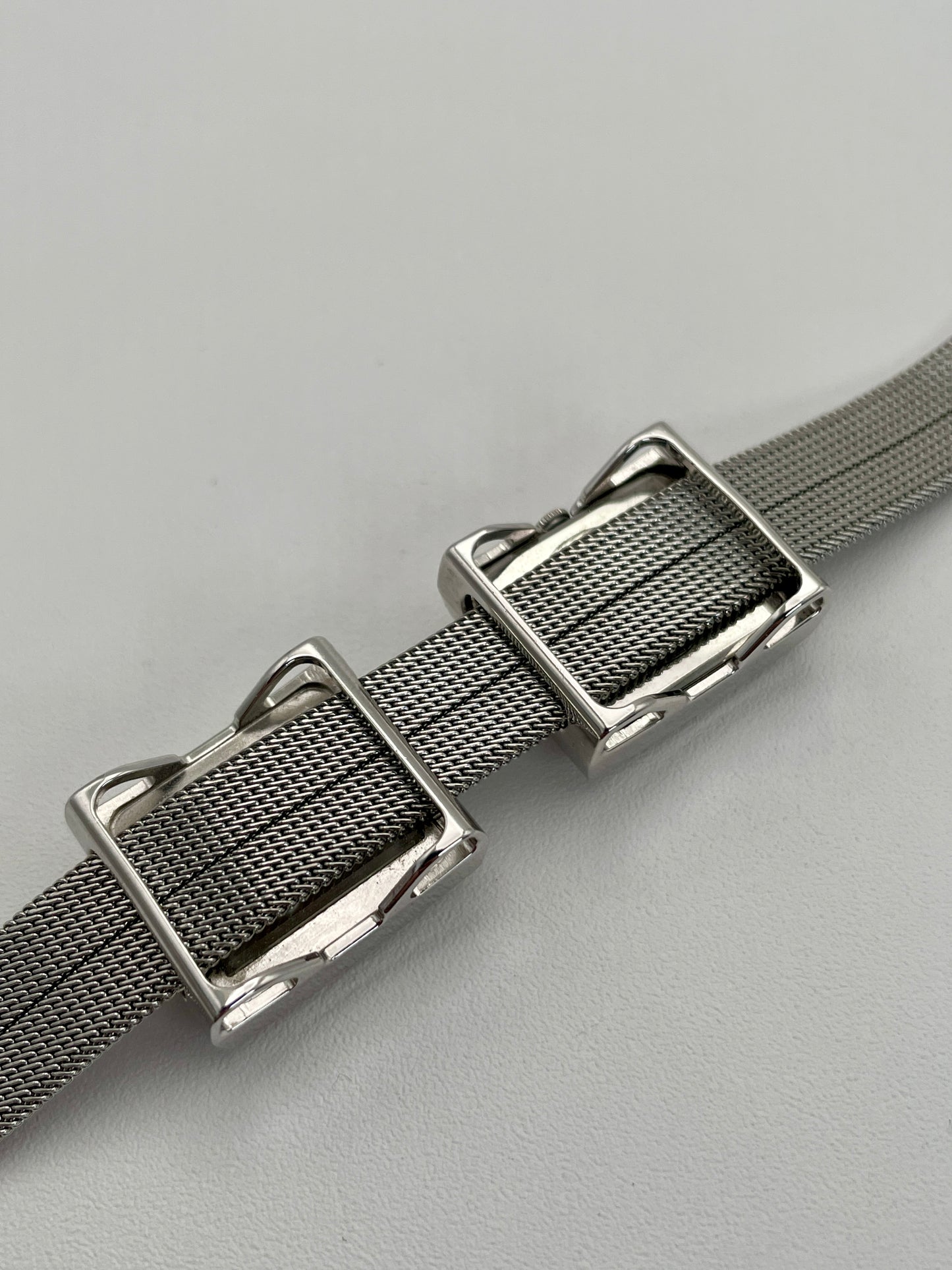 Caseback view of a Mikimoto ladies' watch showing the polished silver-tone back and the intricate mesh bracelet.