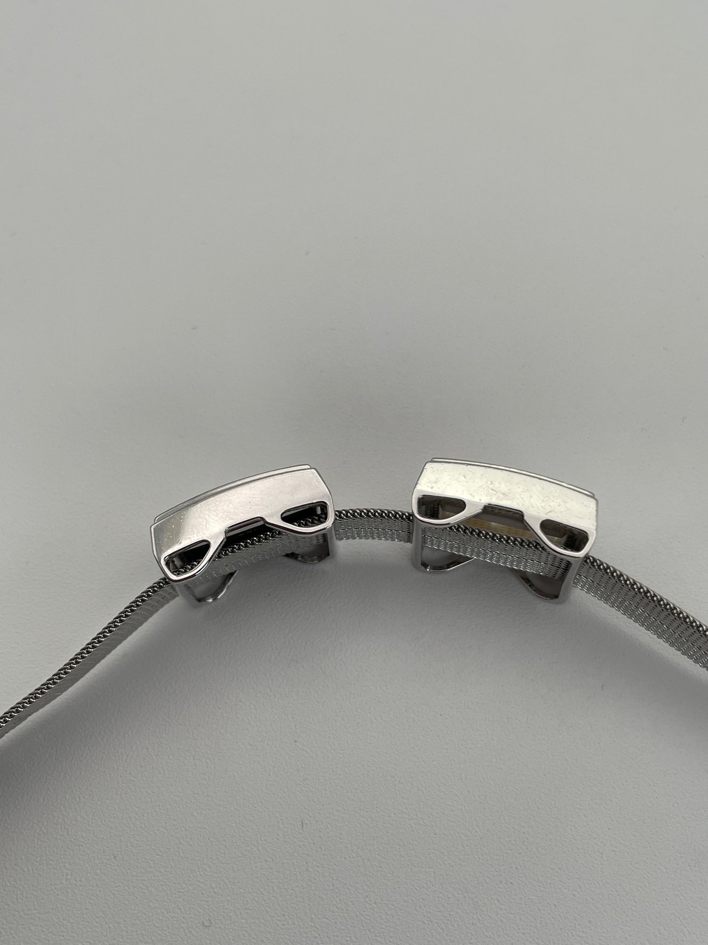 Side profile of a Mikimoto ladies' watch, emphasizing the sleek silver-tone case, the side view of the bracelet window with pearls, and the mesh bracelet's detailed craftsmanship.