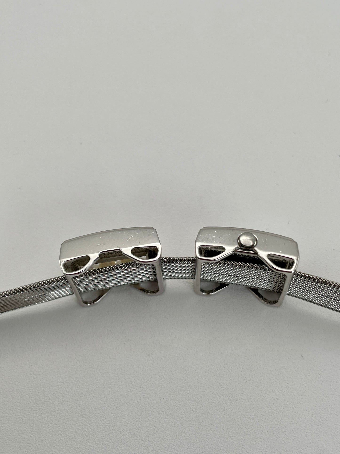 Side profile of a Mikimoto ladies' watch, emphasizing the sleek silver-tone case, the side view of the bracelet window with pearls, and the mesh bracelet's detailed craftsmanship.