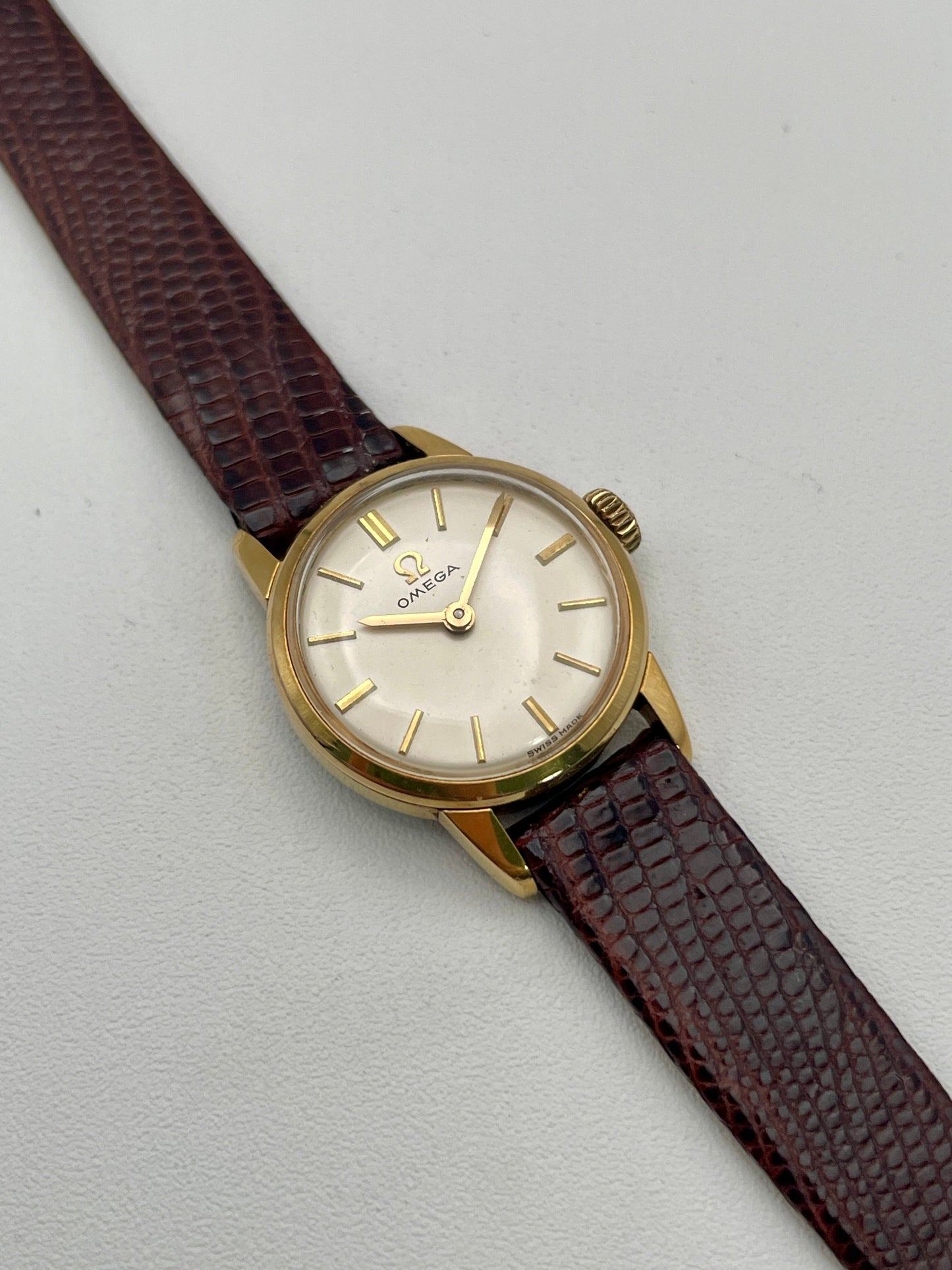 Main view of an Omega 511.015 Vintage Women's Watch in gold with a cream dial and gold baton indices, paired with a brown leather strap.