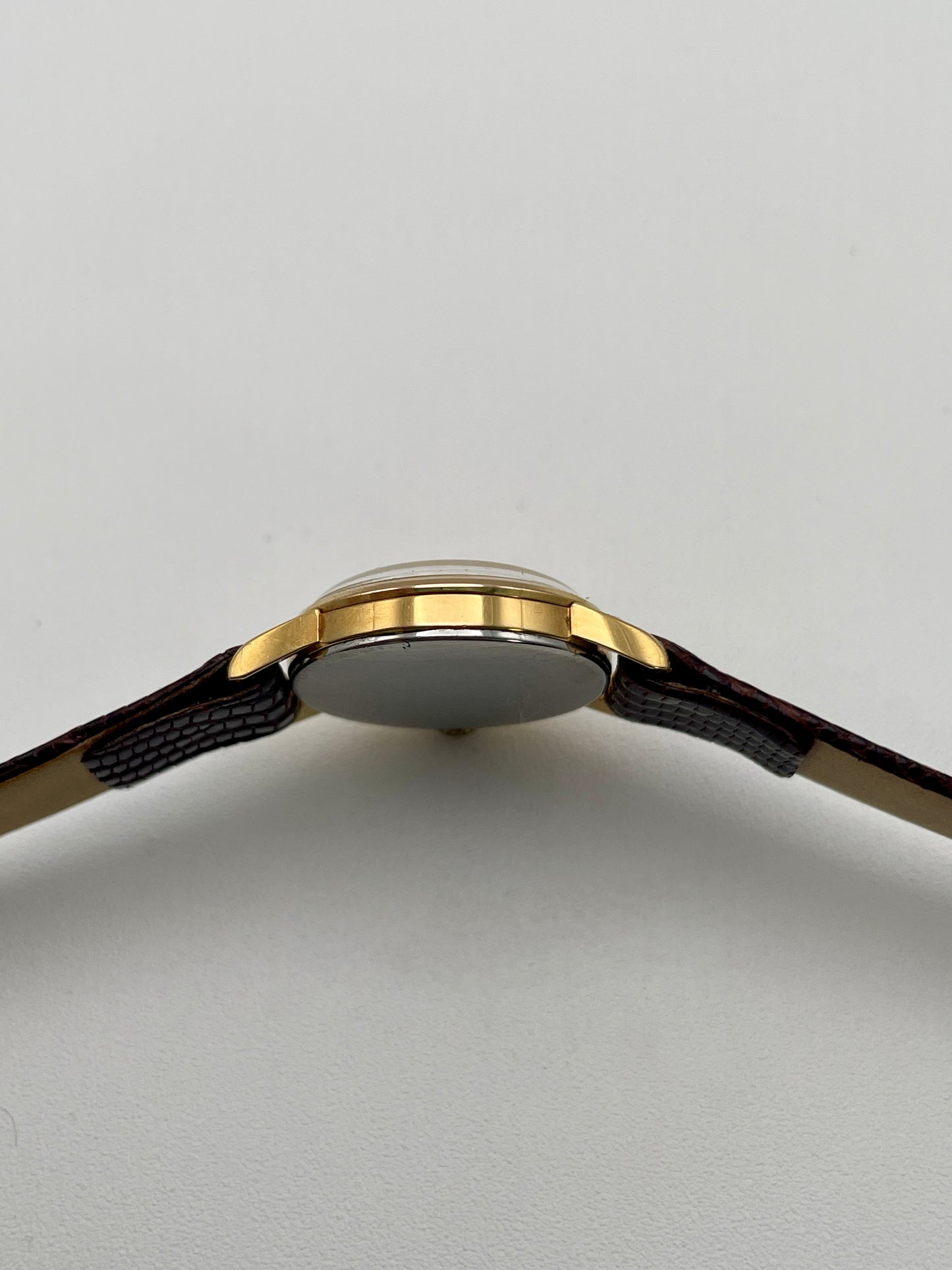 Side profile of an Omega 511.015 Vintage Women's Watch in gold, highlighting the slim case design and lizard-textured strap.