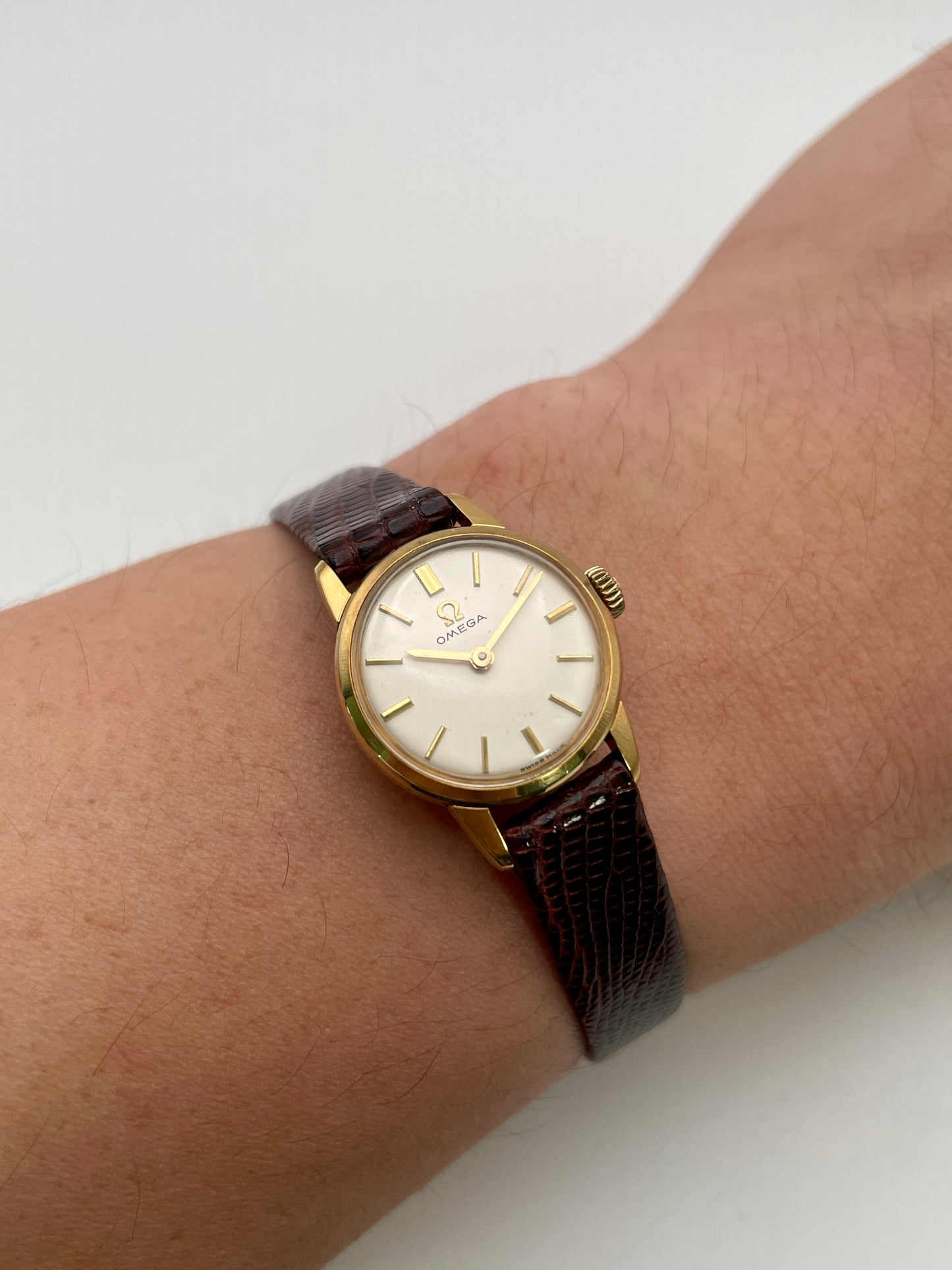 Wrist shot of an Omega 511.015 Vintage Women's Watch in gold, paired with a brown lizard-textured leather strap, worn for a classic look.