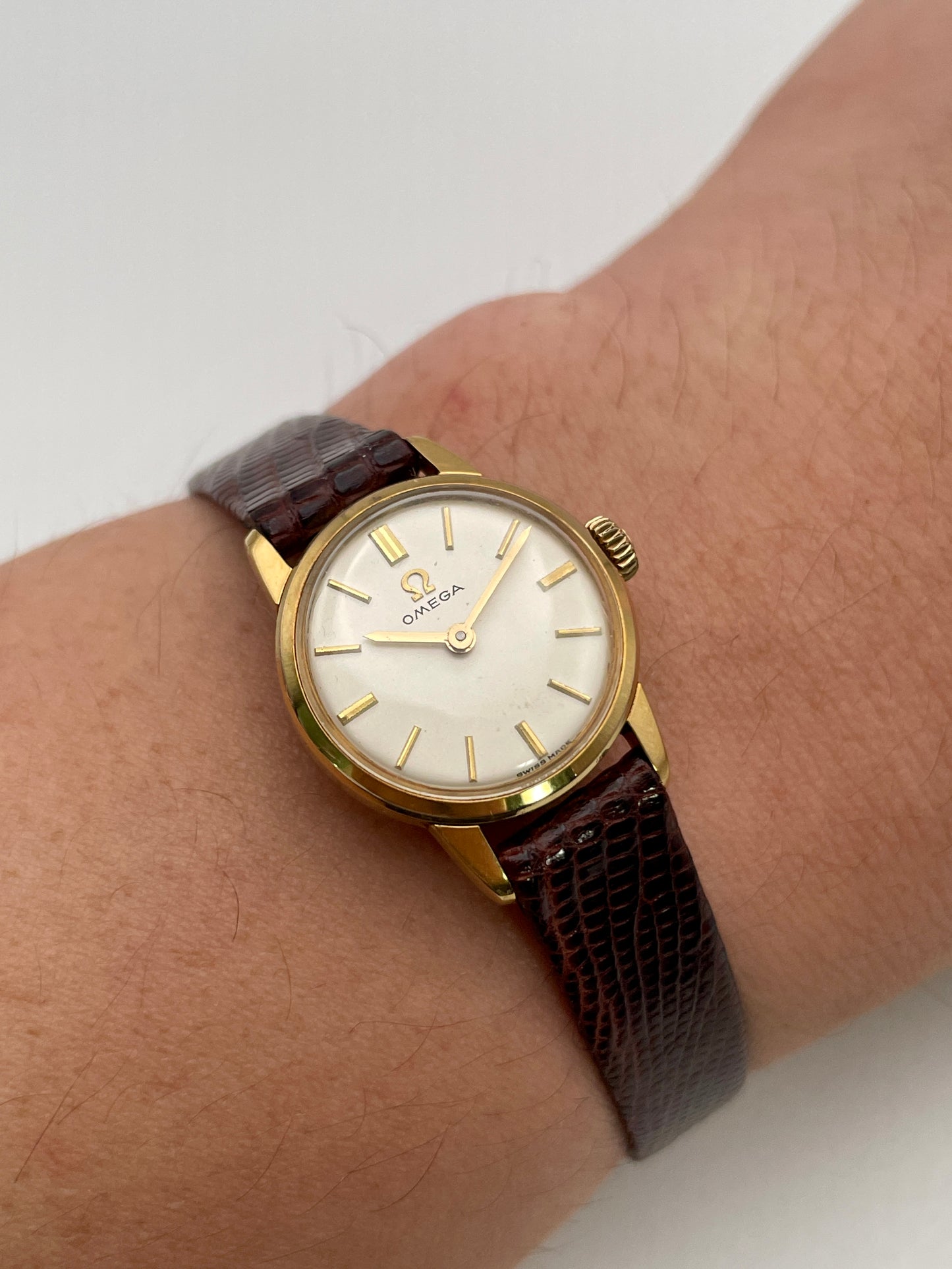 Wrist shot of an Omega 511.015 Vintage Women's Watch in gold, paired with a brown lizard-textured leather strap, worn for a classic look.