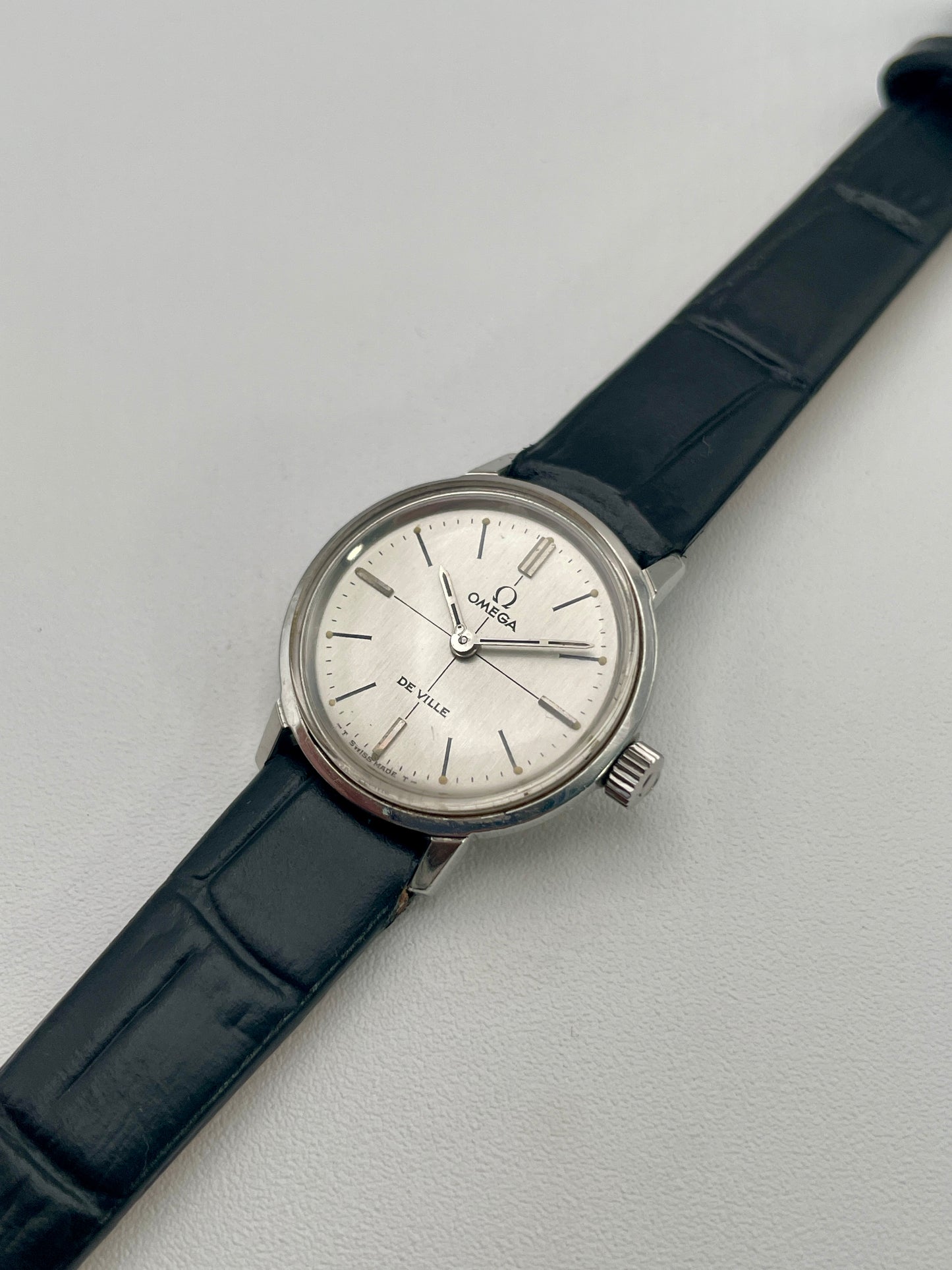 Angled view of the Omega De Ville 515.007 vintage watch highlighting its polished stainless steel case and elegant silver sunburst dial.