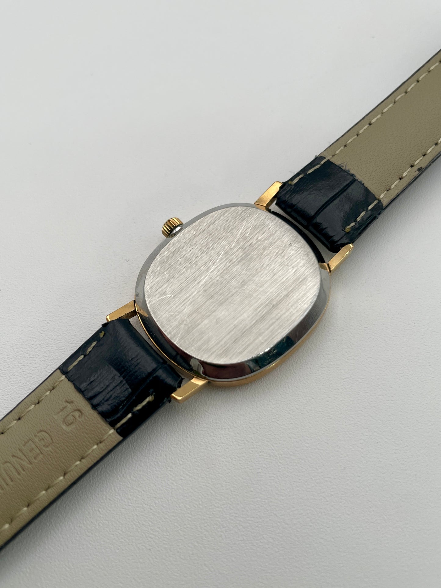 Caseback view of the Omega De Ville Oval watch in gold with a black leather strap.