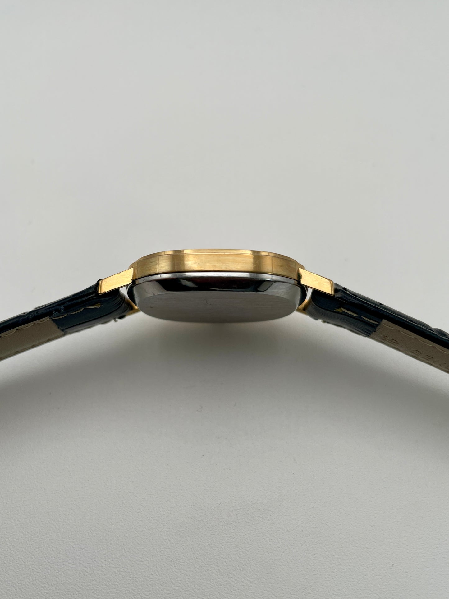 Omega De Ville Oval watch side view, highlighting the gold case.