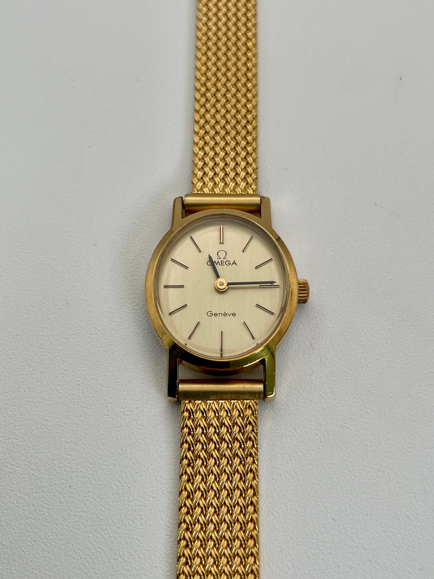 Omega Genève oval ladies watch in gold with a mesh bracelet, front view.