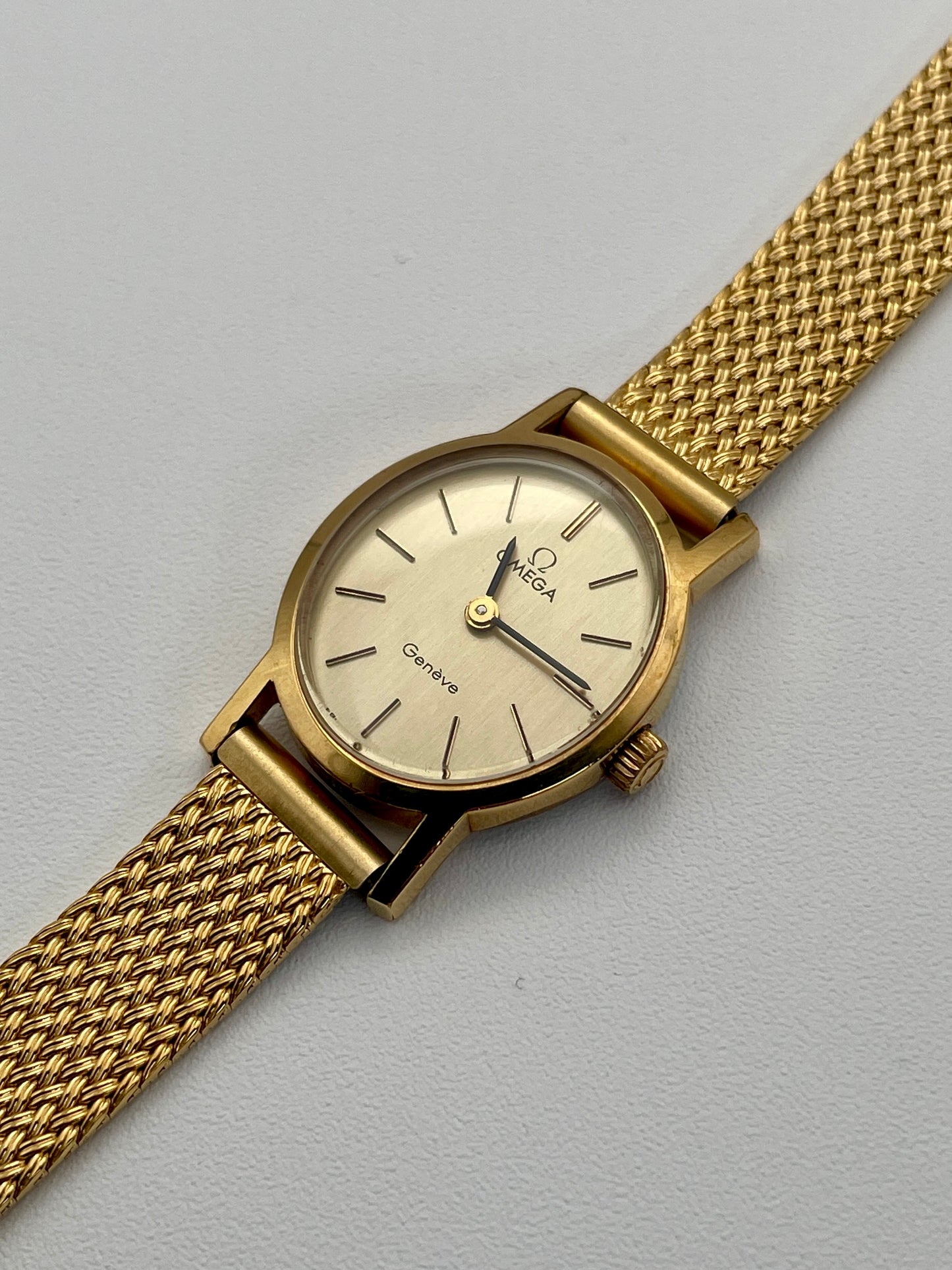 Omega Genève oval ladies watch in gold with a mesh bracelet, full front view.