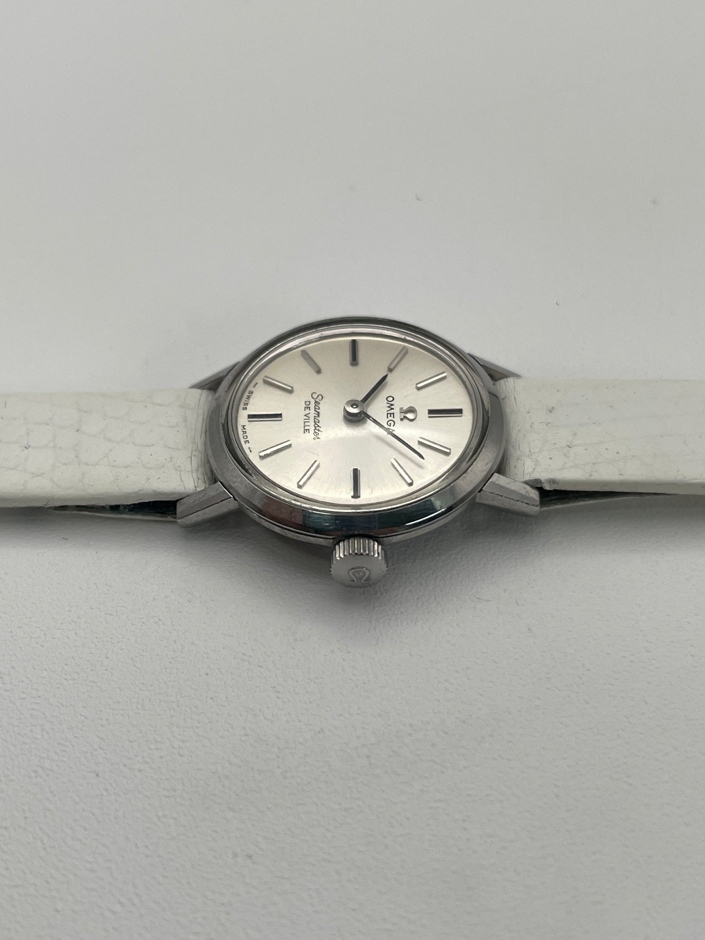Side view of the Omega Seamaster De Ville ladies watch, highlighting the crown and case detail alongside the white leather strap.
