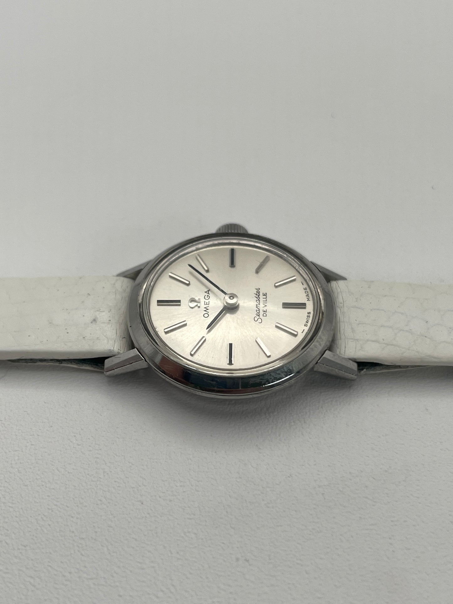 Side view of the Omega Seamaster De Ville ladies watch, highlighting the slim profile case and case detail alongside the white leather strap.