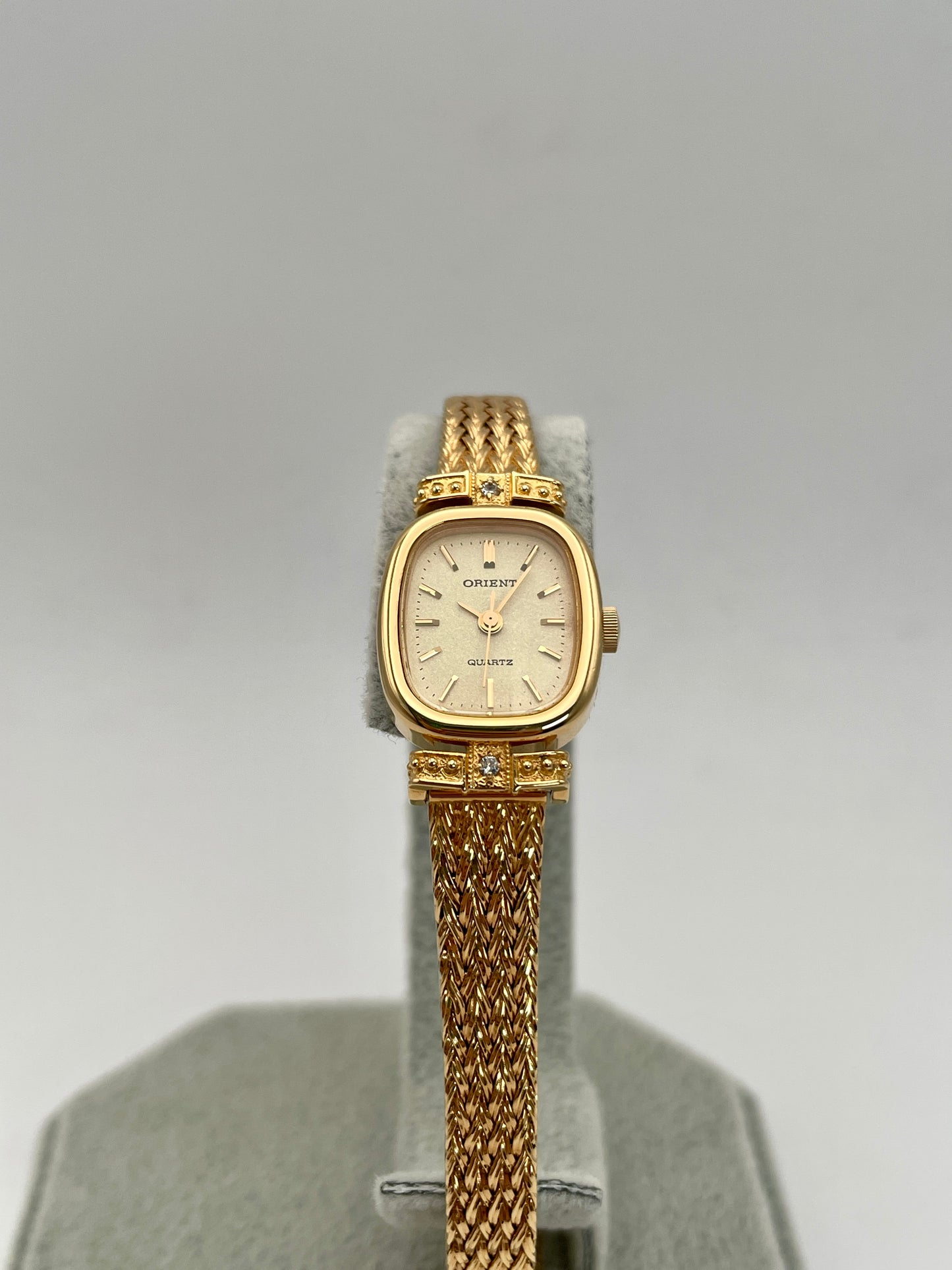 Front view of Orient Vintage Women's Watch in gold with champagne dial and diamond accents on a display stand.