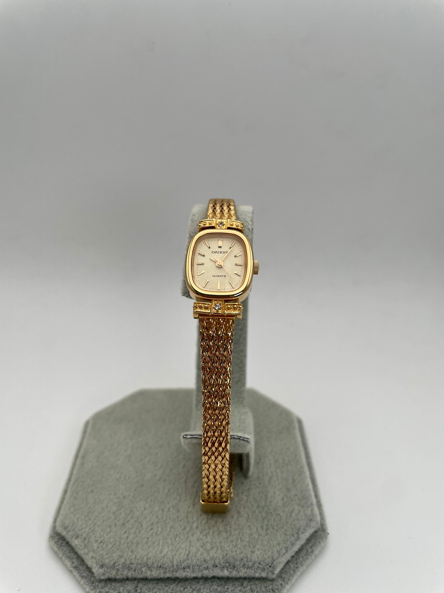 Front view of Orient Vintage Women's Watch in gold with champagne dial and diamond accents on a display stand.