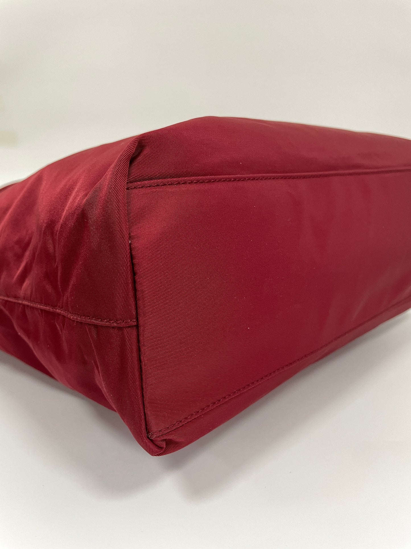 Bottom corner view of the Prada Tessuto Tote Bag in red nylon showcasing the smooth and clean finish.