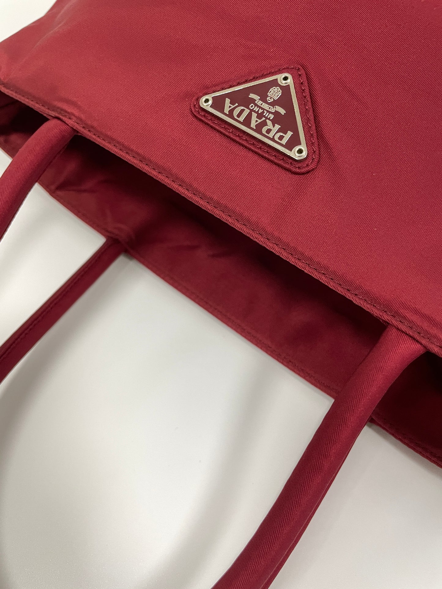 Close-up view of the handles and stitching details on the Prada Tessuto Tote Bag in red nylon.
