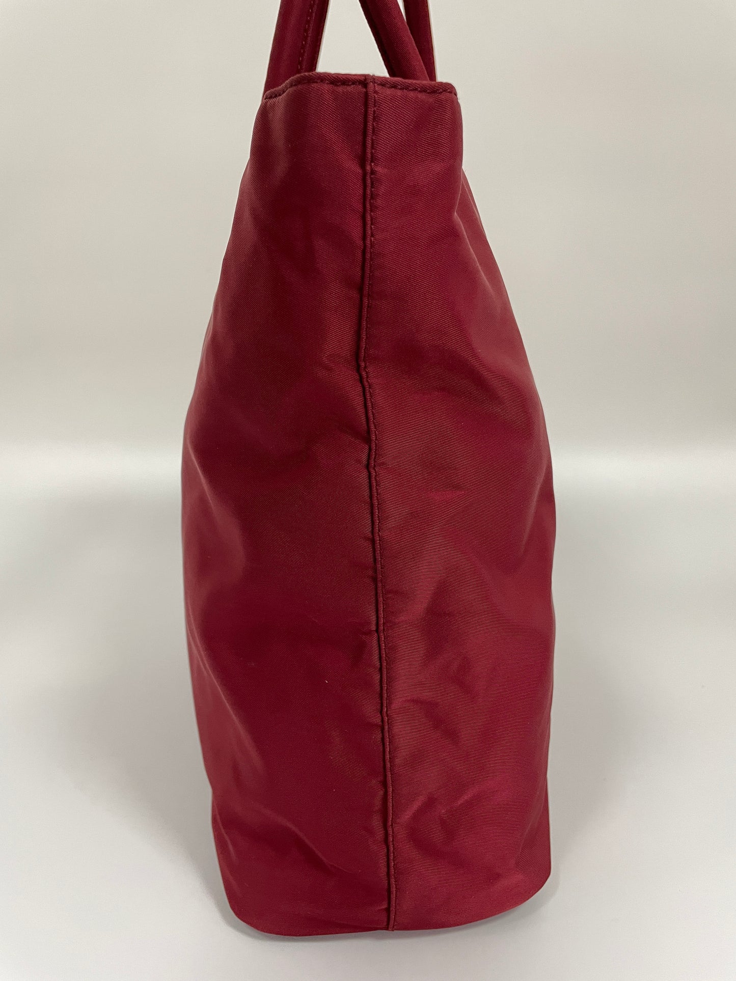 Side view of the Prada Tessuto Tote Bag in red nylon, highlighting the structure and shape of the bag.