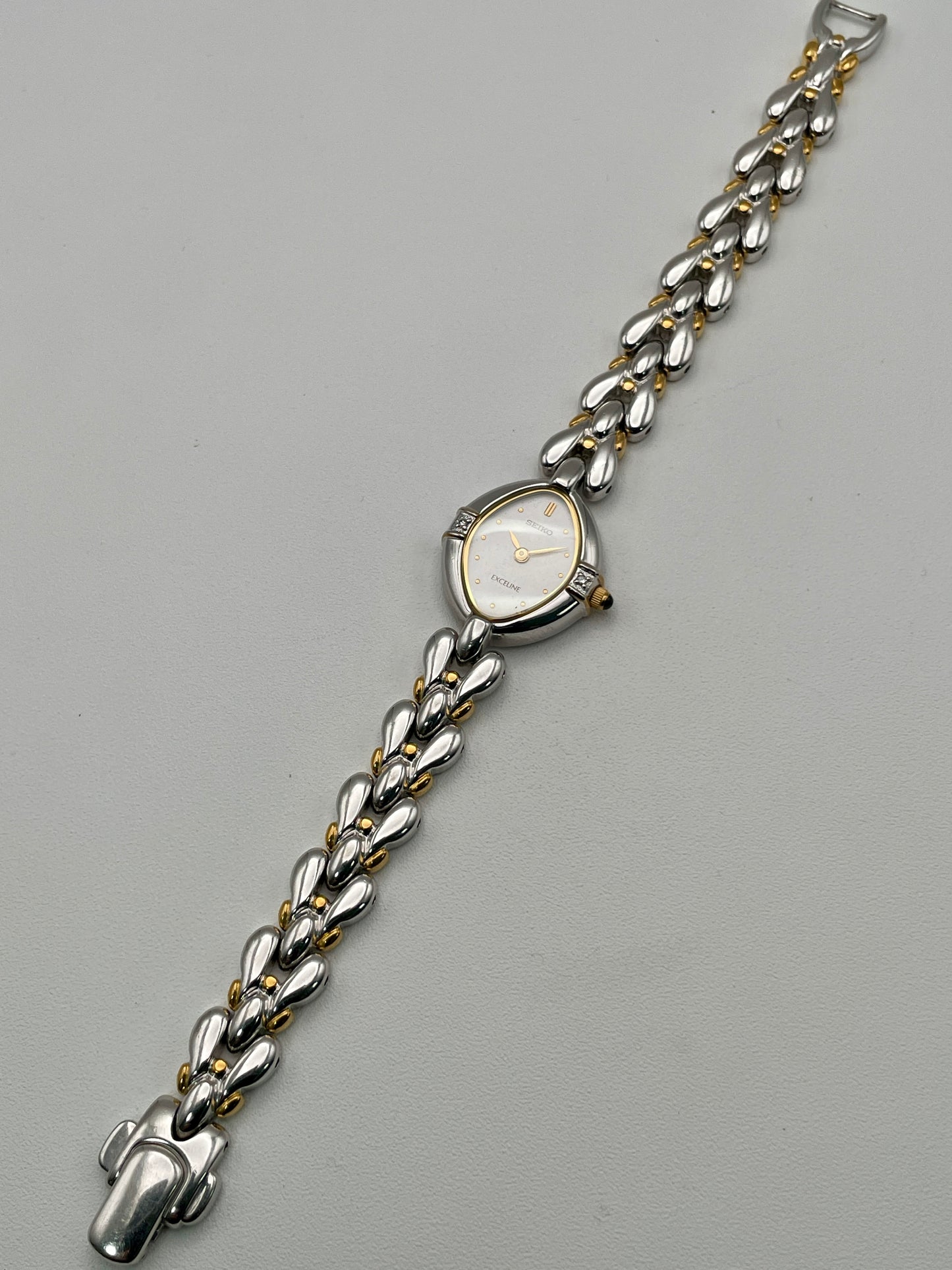 Full watch view laid flat, displaying the entire bracelet and teardrop case
