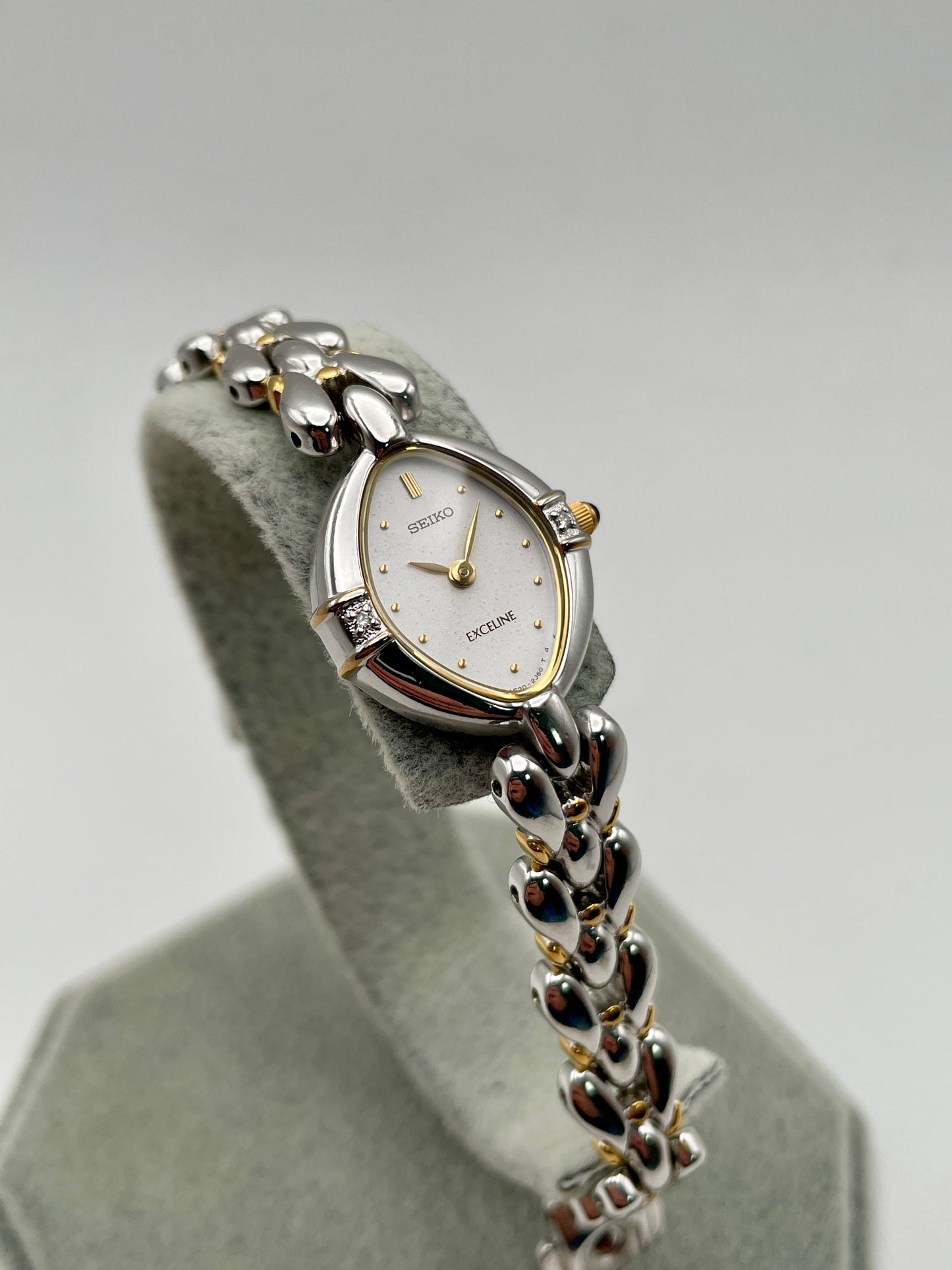 Seiko Exceline 1F20-6B60 vintage women's watch with teardrop case and two-tone bracelet, front view on display stand
