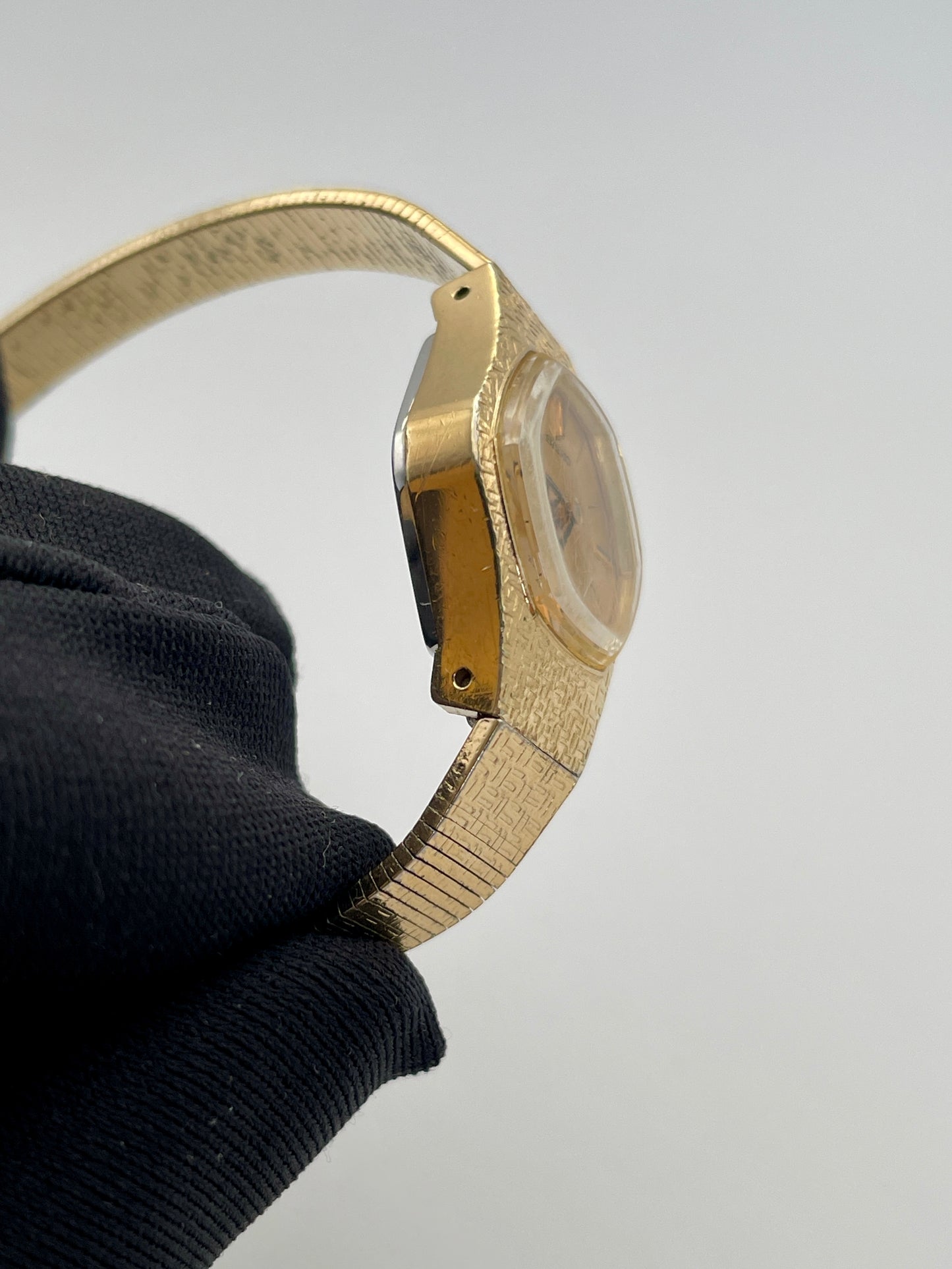 Side profile of a vintage Seiko ladies' watch showcasing its gold-tone textured case and bracelet, highlighting the slender profile and the integrated design of the bracelet.