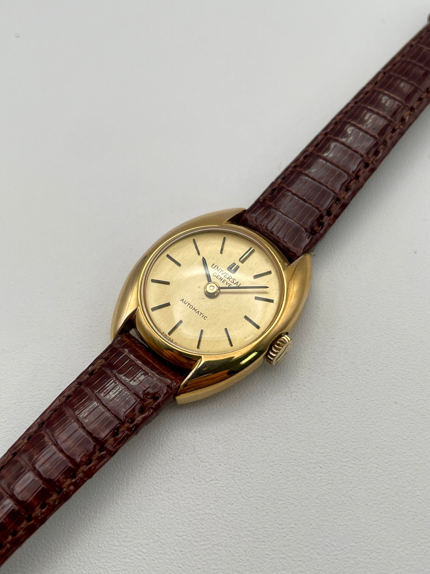 Diagonal view showing the gold case and champagne dial of the Universal Geneve watch