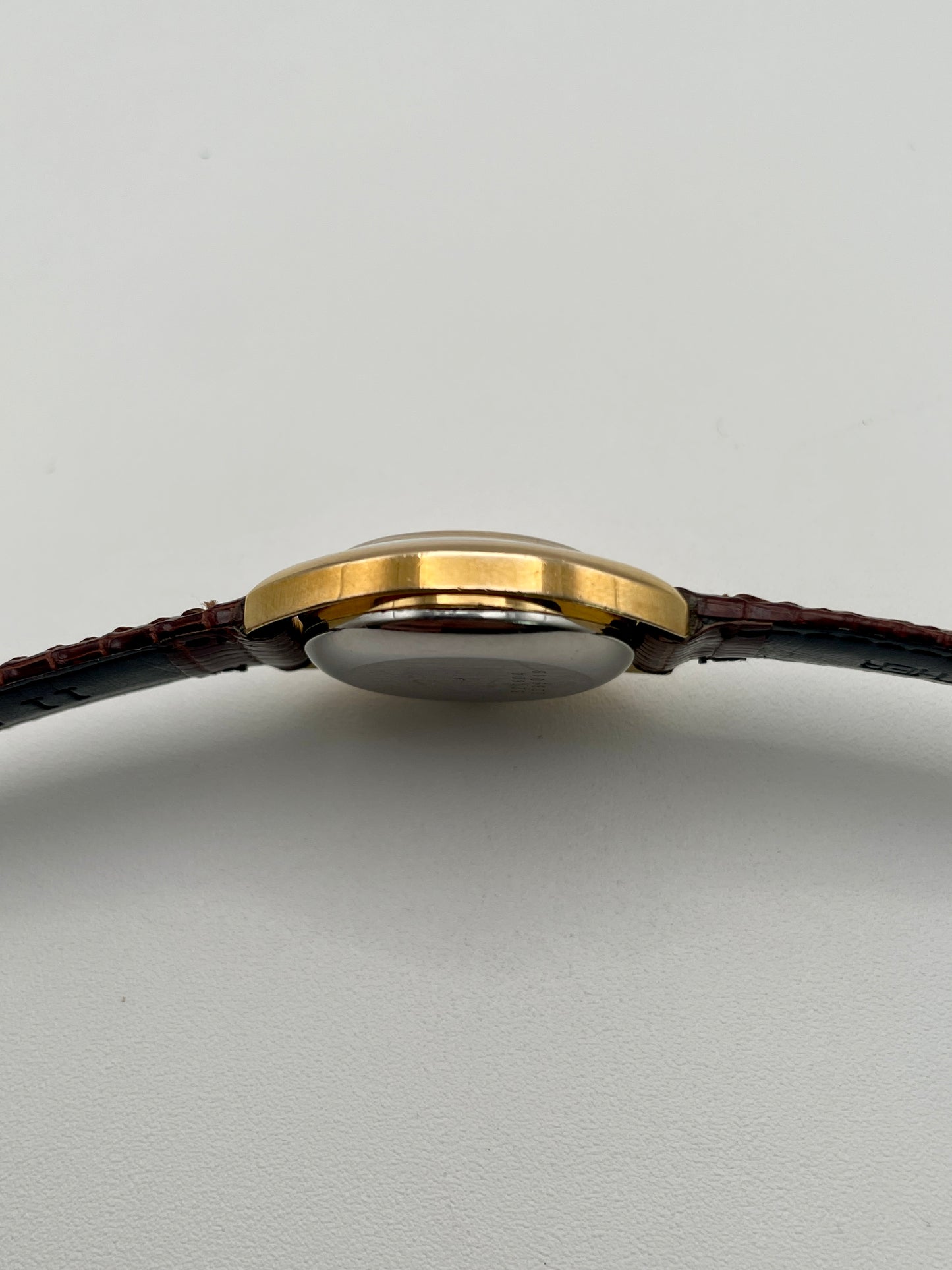 Side profile showing the slim gold case and domed crystal