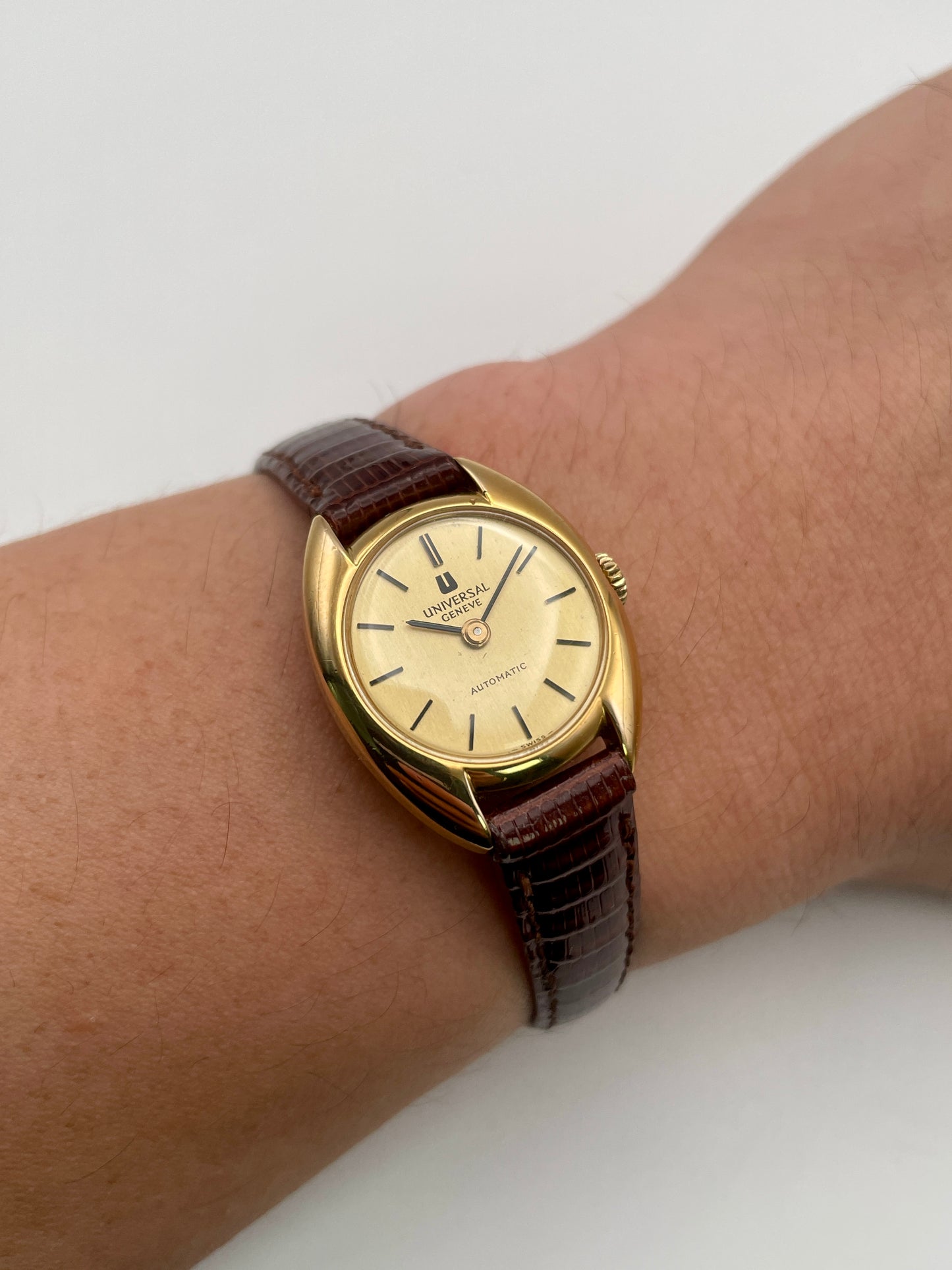 Wrist shot showing the Universal Geneve gold watch worn with brown leather strap